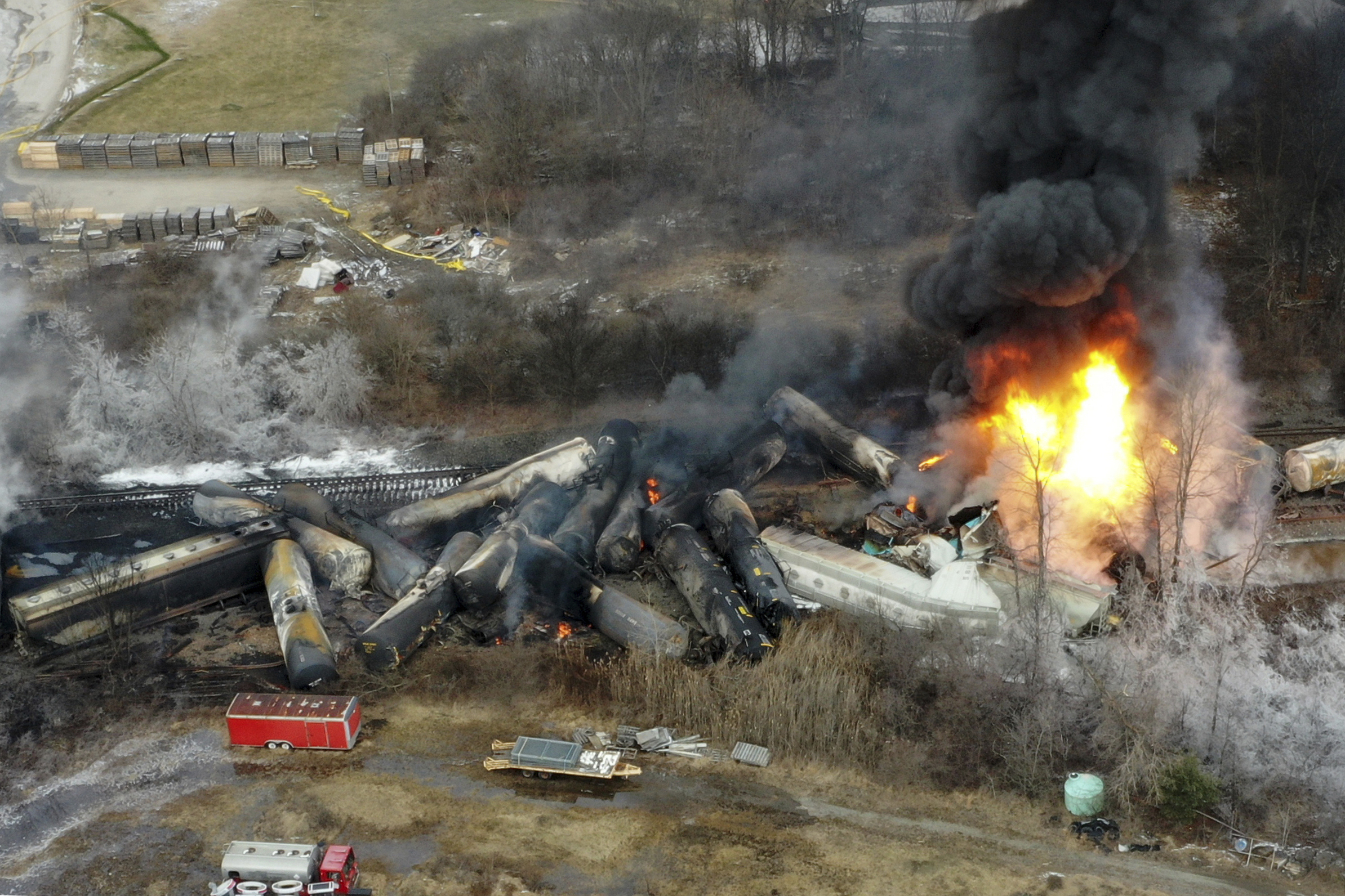 FILE - Portions of a Norfolk Southern freight train that derailed the night before burn in East Palestine, Ohio, Feb. 4, 2023. Norfolk Southern railroad announced on Tuesday, Dec. 4, plans to stop paying relocation aid to people displaced by the derailment right after the one-year anniversary of the crash. Railroad officials reiterated their long-term commitment to helping the town of East Palestine and the surrounding area recover. (AP Photo/Gene J. Puskar, File)