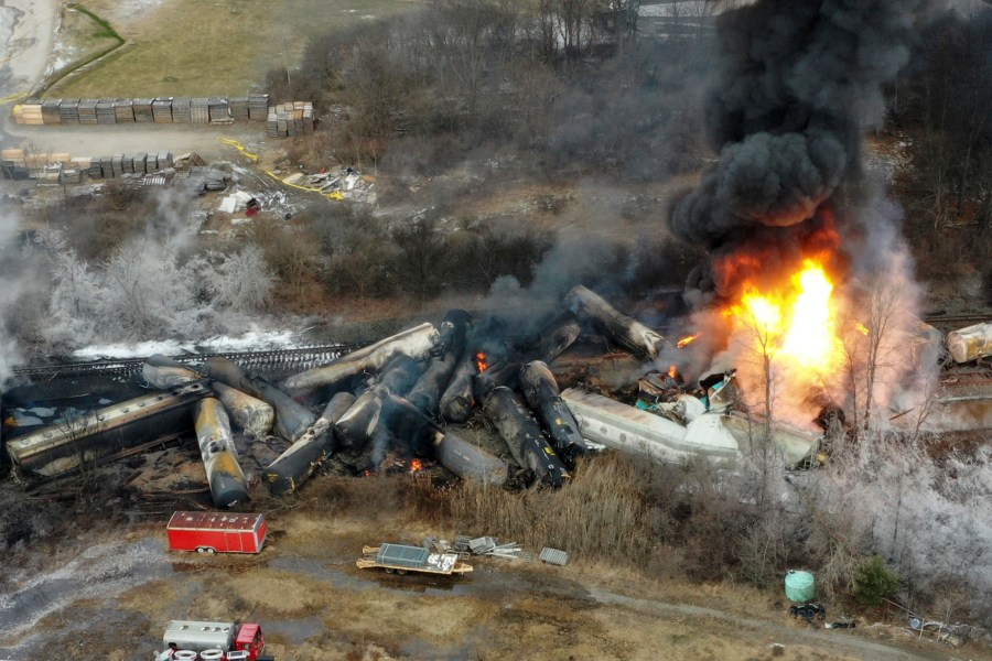 FILE - Portions of a Norfolk Southern freight train that derailed the night before burn in East Palestine, Ohio, Feb. 4, 2023. Norfolk Southern railroad announced on Tuesday, Dec. 4, plans to stop paying relocation aid to people displaced by the derailment right after the one-year anniversary of the crash. Railroad officials reiterated their long-term commitment to helping the town of East Palestine and the surrounding area recover. (AP Photo/Gene J. Puskar, File)