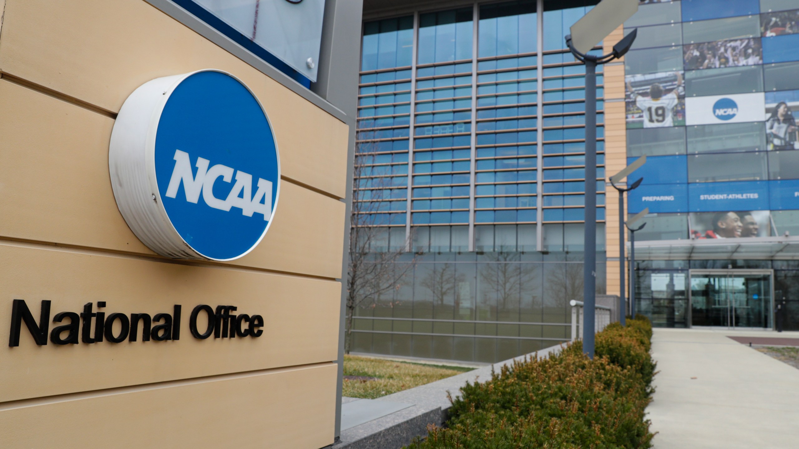 FILE - This is a March 12, 2020, file photo showing NCAA headquarters in Indianapolis. A lawsuit filed in West Virginia’s northern district challenges the NCAA’s authority to impose a one-year delay in the eligibility of certain athletes who transfer between schools. The suit said the rule “unjustifiably restrains the ability of these college athletes to engage in the market for their labor as NCAA Division I college athletes.”(AP Photo/Michael Conroy, File)