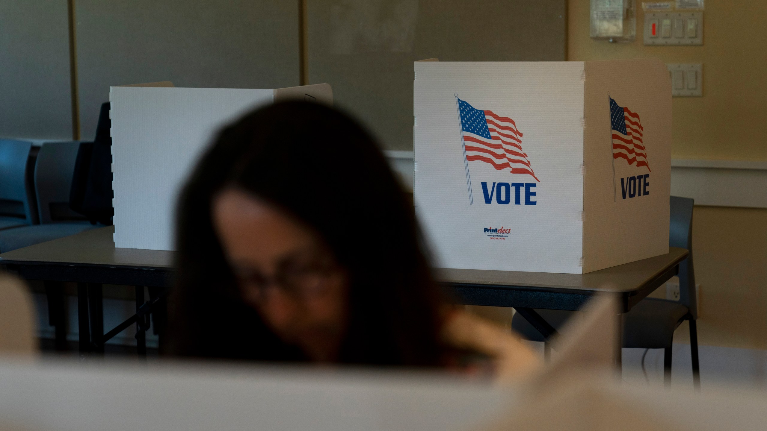 FILE - A voter in the foreground casts her ballots during the Republican primary election in Wilson, Wyo., Aug. 16, 2022. Relatively few Americans are excited about a potential rematch of the 2020 election between President Joe Biden and Donald Trump. But more Republicans would be happy to have Trump as their nominee than Democrats would be with Biden. That's according to a new poll from The Associated Press-NORC Center for Public Affairs Research. (AP Photo/Jae C. Hong, File)