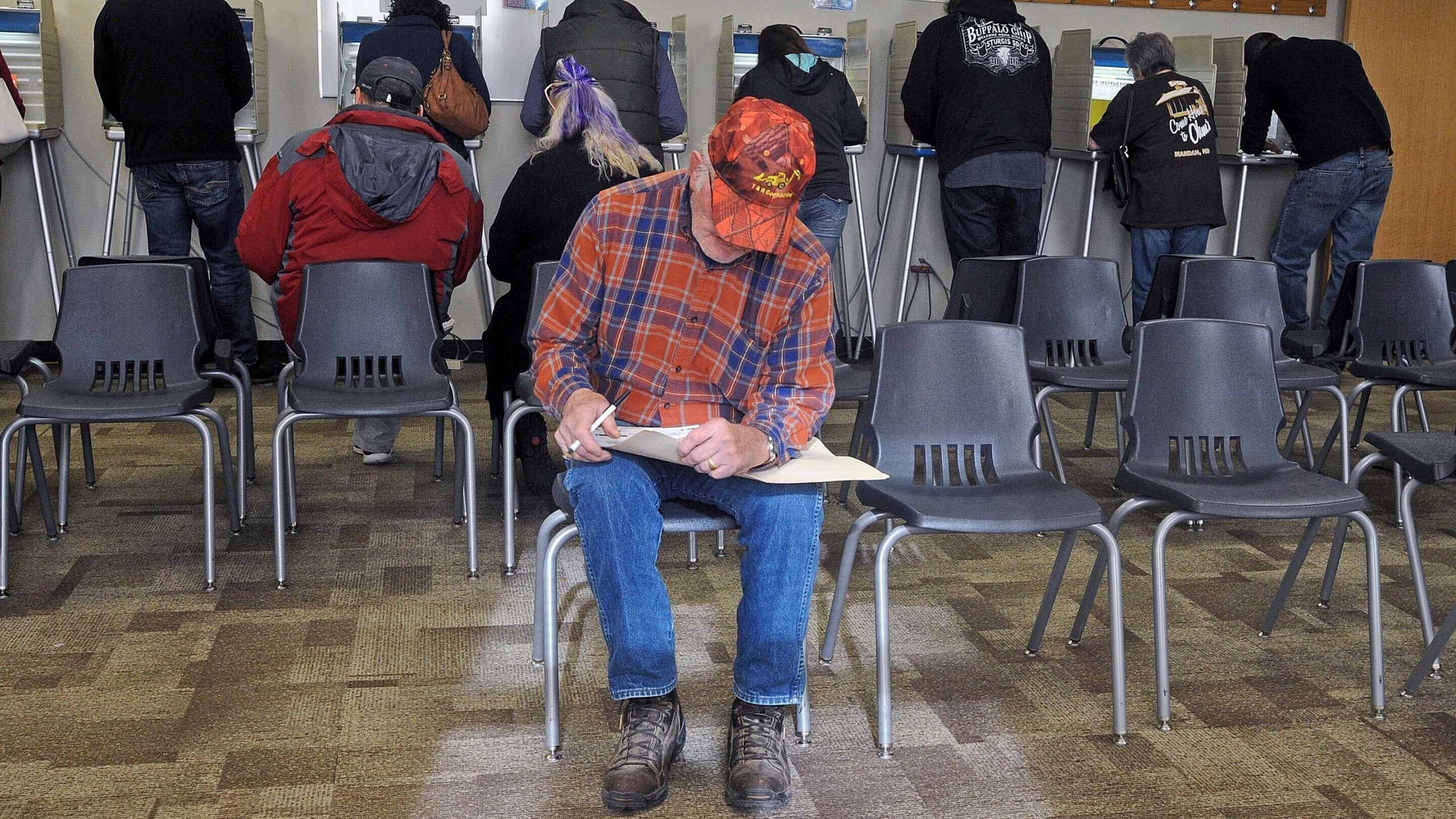 FILE - With all the voting booths filled with people, Ronald Moffit sits down to complete his ballot inside Lincoln City Hall, Nov. 8, 2016, in Lincoln, N.D. North Dakota would become the first state to require hand-counting of all election ballots if voters back a proposed ballot measure that would achieve a goal of activists across the country who distrust modern vote counting. (Tom Stromme/The Bismarck Tribune via AP, File)