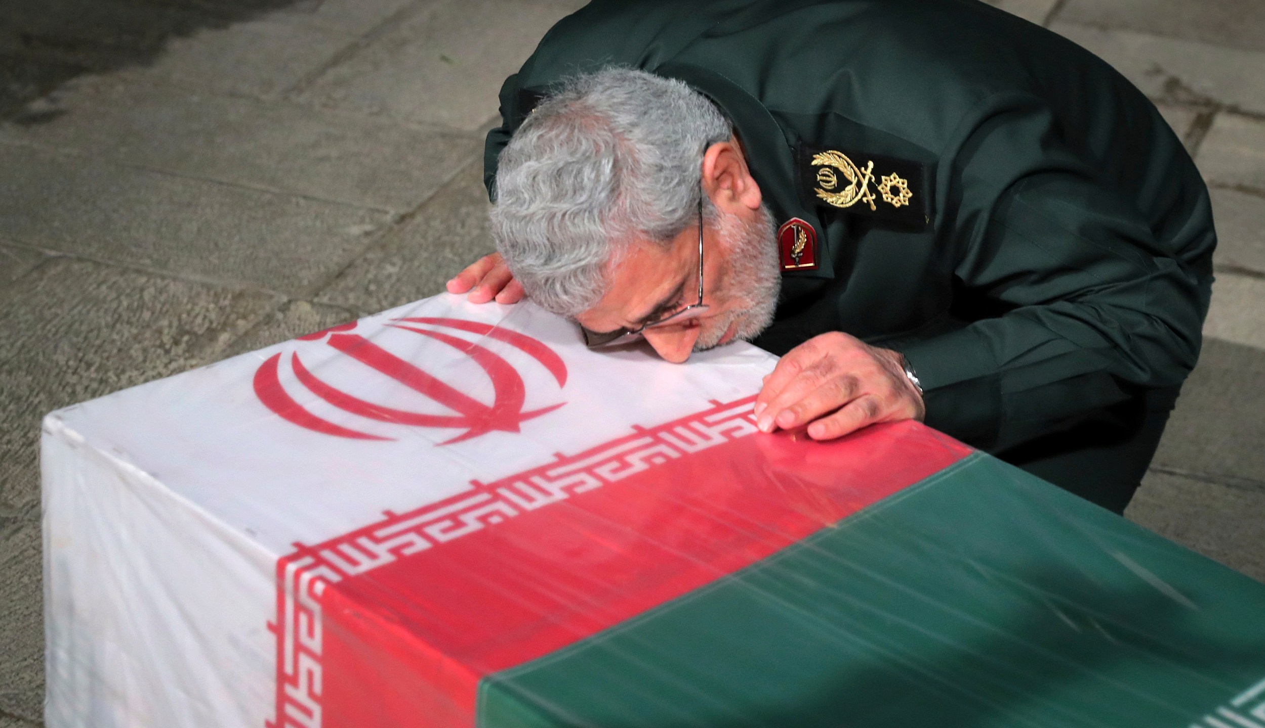 In this photo released by an official website of the office of the Iranian supreme leader, head of Iran's expeditionary Quds Force, Gen. Esmail Ghaani, places his face on the flag-draped coffin of Seyed Razi Mousavi, a high ranking Iranian general of the paramilitary Revolutionary Guard, who was killed in an alleged Israeli airstrike in Syria on Monday, at supreme leader's office compound in Tehran, Iran, Thursday, Dec. 28, 2023. (Office of the Iranian Supreme Leader via AP)