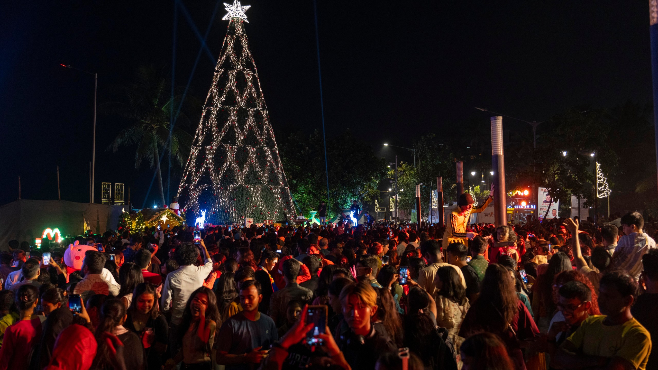 People crowd in front of a decorated Christmas tree at a promenade on the eve of Christmas in Mumbai, India, Sunday, Dec. 24, 2023. Although Christians comprise only two percent of the population Christmas is a national holiday and is observed across the country as an occasion to celebrate. (AP Photo/Rafiq Maqbool)