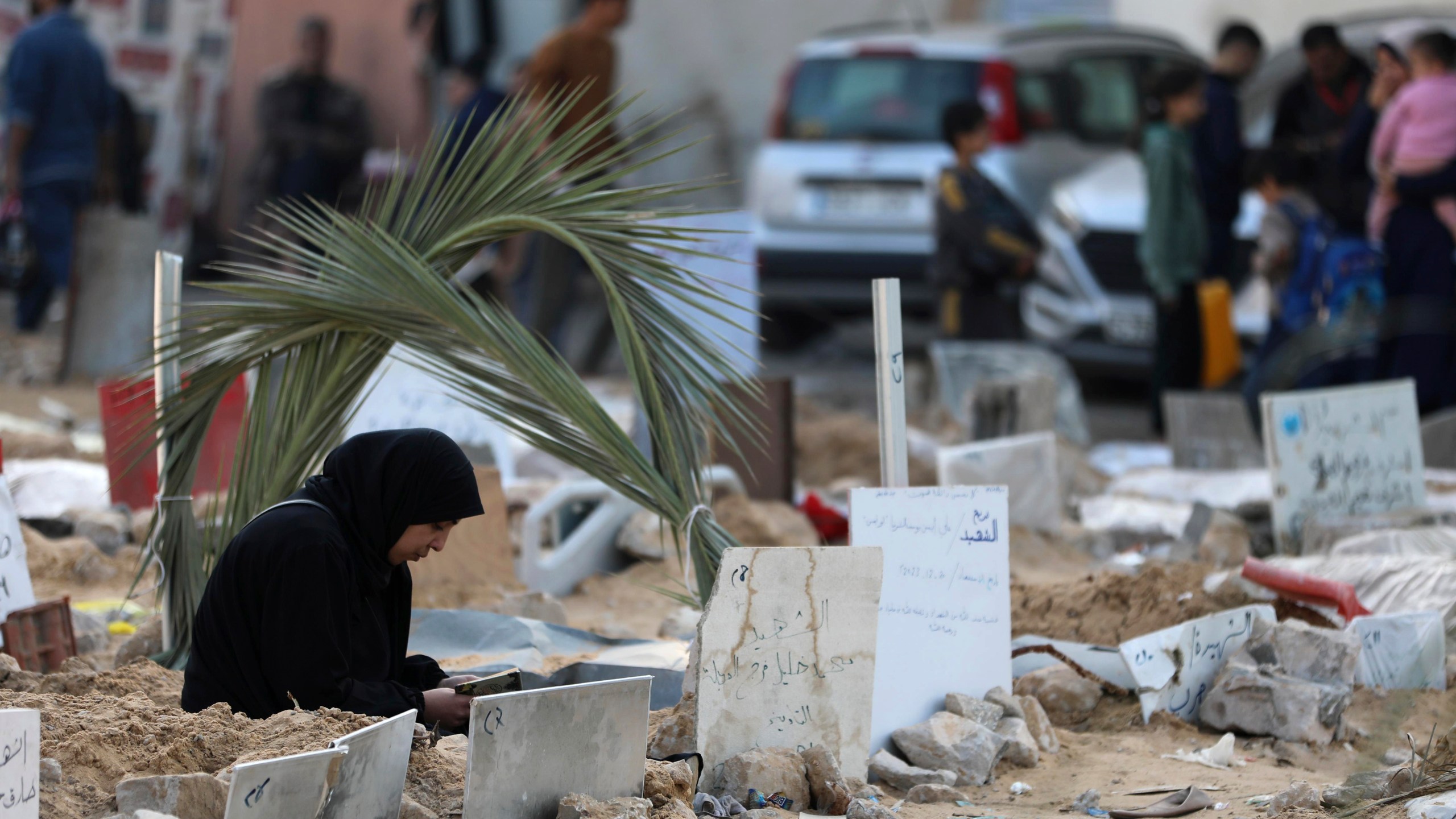 Palestinians visit the graves of people killed in the Israeli bombardment of the Gaza Strip and buried inside the Shifa Hospital grounds in Gaza City, Sunday, Dec. 31, 2023. (AP Photo/Mohammed Hajjar)