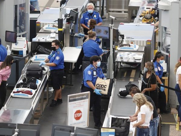 TSA agents screen passengers at an airport.