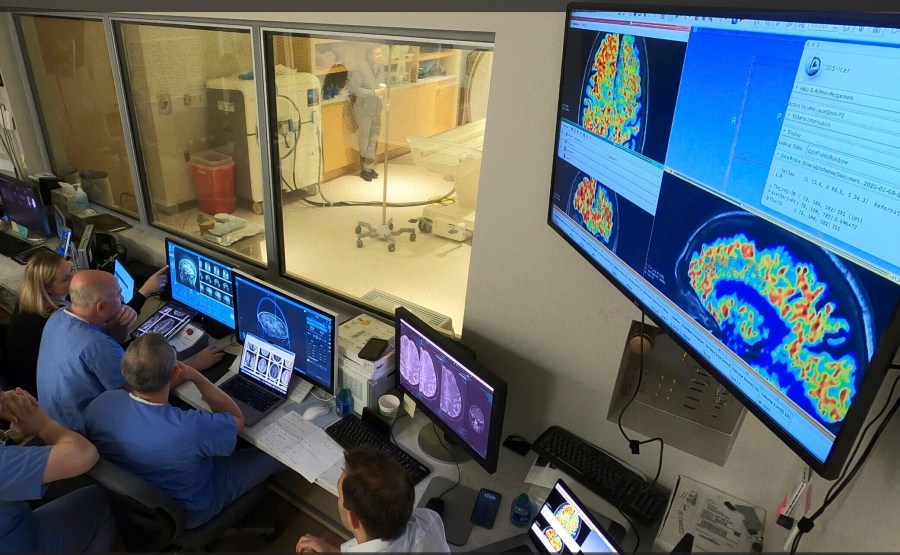 In this photo provided by the WVU Rockefeller Neuroscience Institute, the WVU RNI team in the MRI suite’s control area, plans ultrasound blood-brain barrier treatment in Morgantown, W.Va., on April 11, 2023. Scientists have found a way to help Alzheimer’s drugs seep inside the brain faster _ by temporarily breaching its protective shield. (Victor Finomore/WVU Rockefeller Neuroscience Institute via AP)