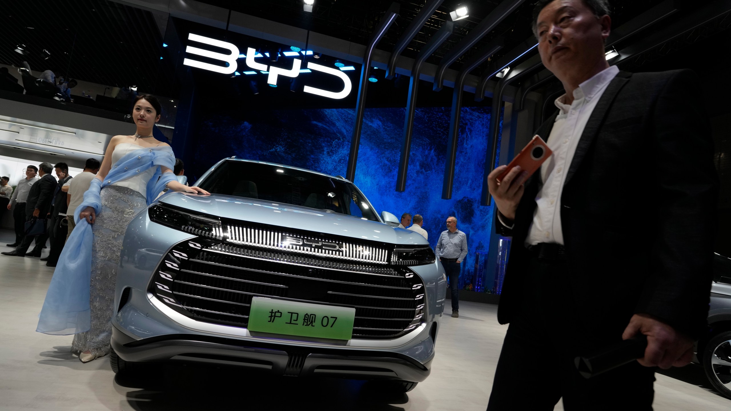 FILE - A model stands next to a car from BYD during the Shanghai auto show in Shanghai, on April 18, 2023. BYD Co., based in the southern China tech hub of Shenzhen, dethroned Texas-based Tesla Inc. as the top seller of electric cars in the last three months of 2023, according to sales figures released by the companies this week. (AP Photo/Ng Han Guan, File)