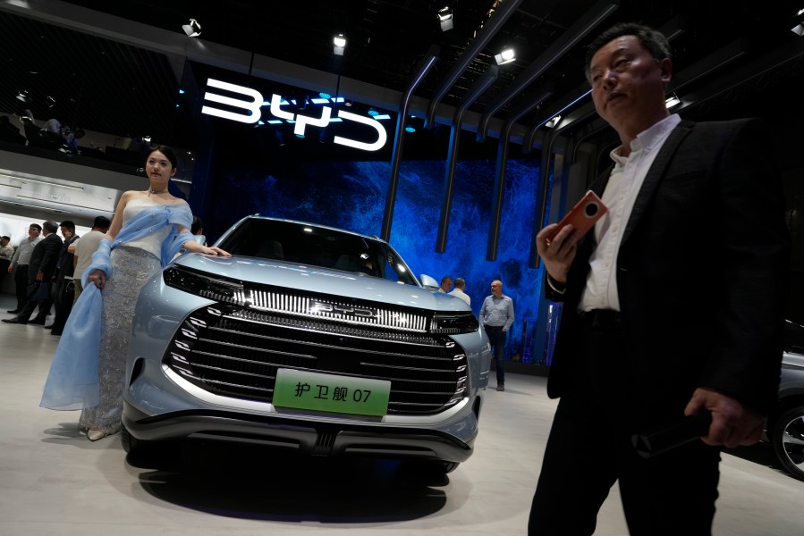 FILE - A model stands next to a car from BYD during the Shanghai auto show in Shanghai, on April 18, 2023. BYD Co., based in the southern China tech hub of Shenzhen, dethroned Texas-based Tesla Inc. as the top seller of electric cars in the last three months of 2023, according to sales figures released by the companies this week. (AP Photo/Ng Han Guan, File)