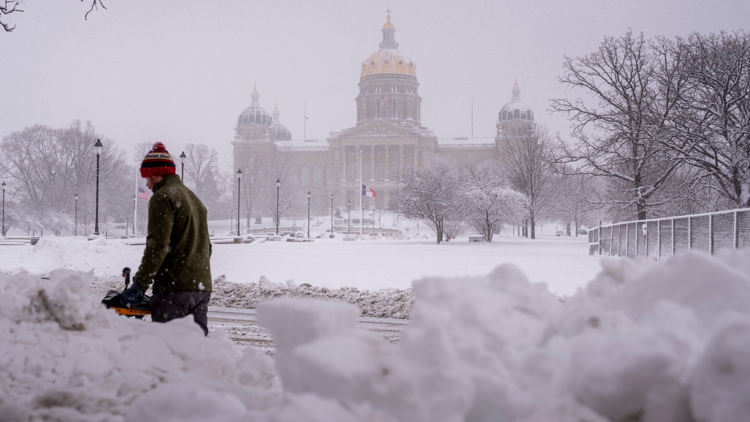 The Iowa State Capitol Building is visible as Spud Glaser of Carlisle, Iowa, plows the sidewalk in downtown Des Moines, Iowa, Tuesday, Jan. 9, 2024, as a winter snow storm hits the state. (AP Photo/Andrew Harnik)