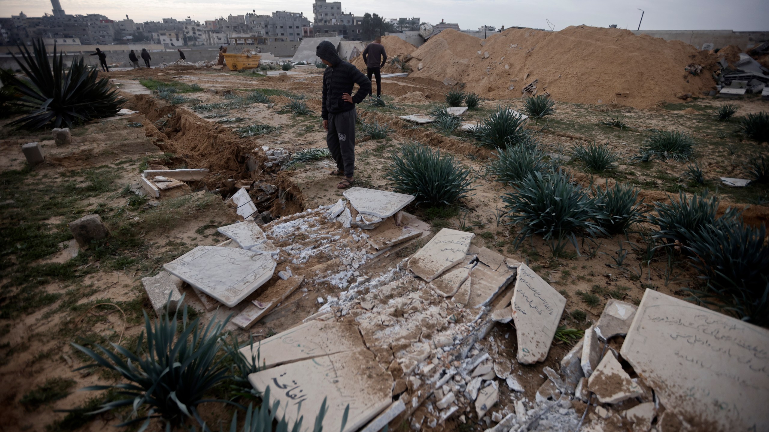 Palestinians inspect damaged graves following an Israeli tanks raid over a cemetery in Khan Younis refugee camp, southern Gaza Strip, Wednesday, Jan. 17, 2024. (AP Photo/Mohammed Dahman)