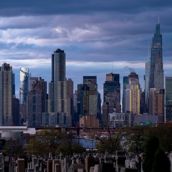 FILE - The sun sets behind the New York skyline, Nov. 13, 2022, as seen from Calvary Cemetery. New York City appears to have gotten an additional 1,090 people added to its population total recently after asking the Census Bureau to double-check the city's numbers from the head count of every U.S. resident, city officials said. (AP Photo/Julia Nikhinson, File)