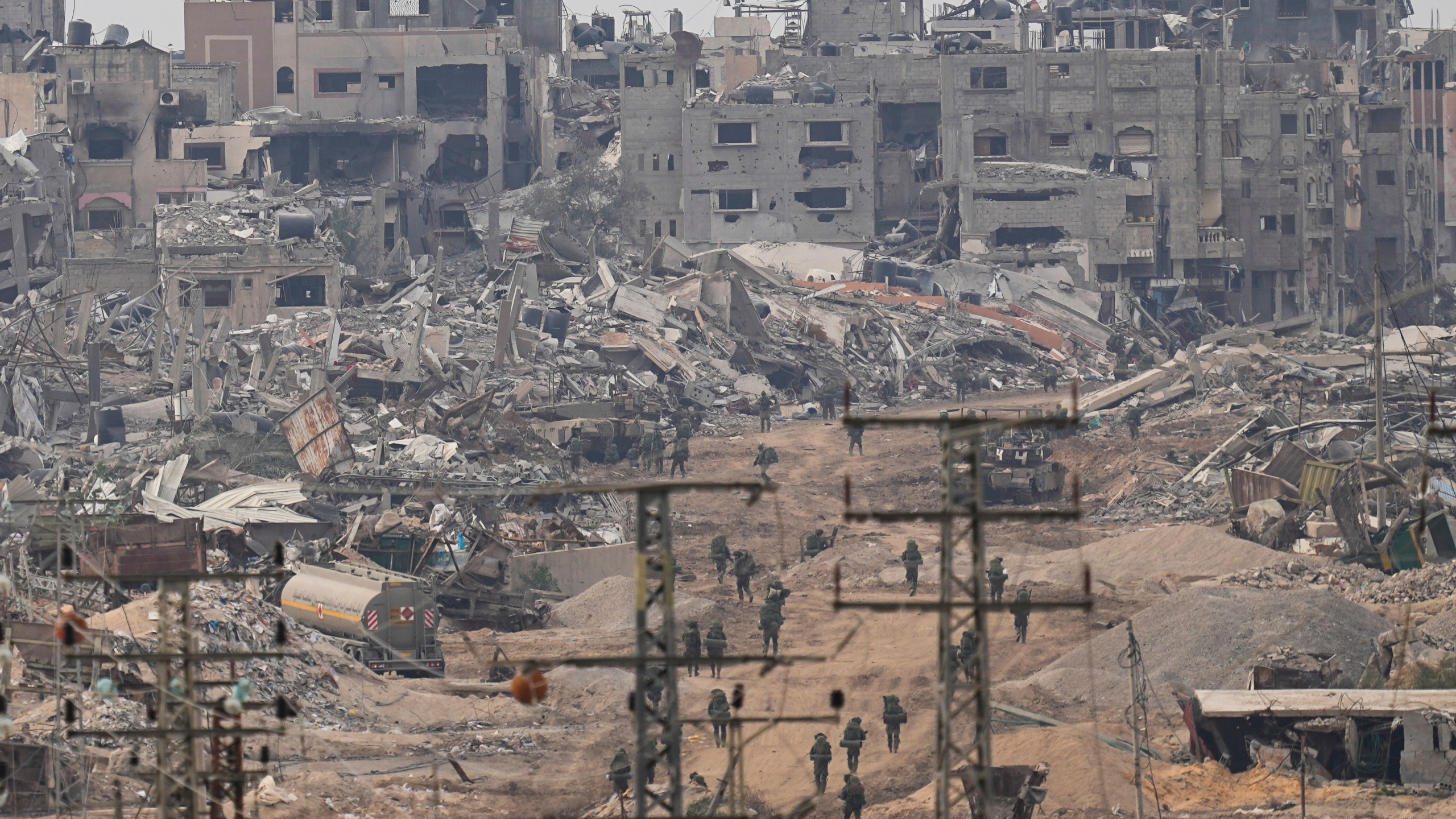 FILE - Israeli troops walk in the Gaza Strip as seen from southern Israel, Dec. 21, 2023. (AP Photo/Ohad Zwigenberg, File)