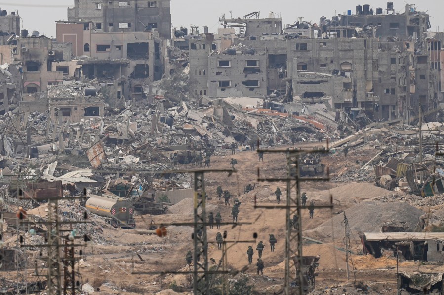 FILE - Israeli troops walk in the Gaza Strip as seen from southern Israel, Dec. 21, 2023. (AP Photo/Ohad Zwigenberg, File)