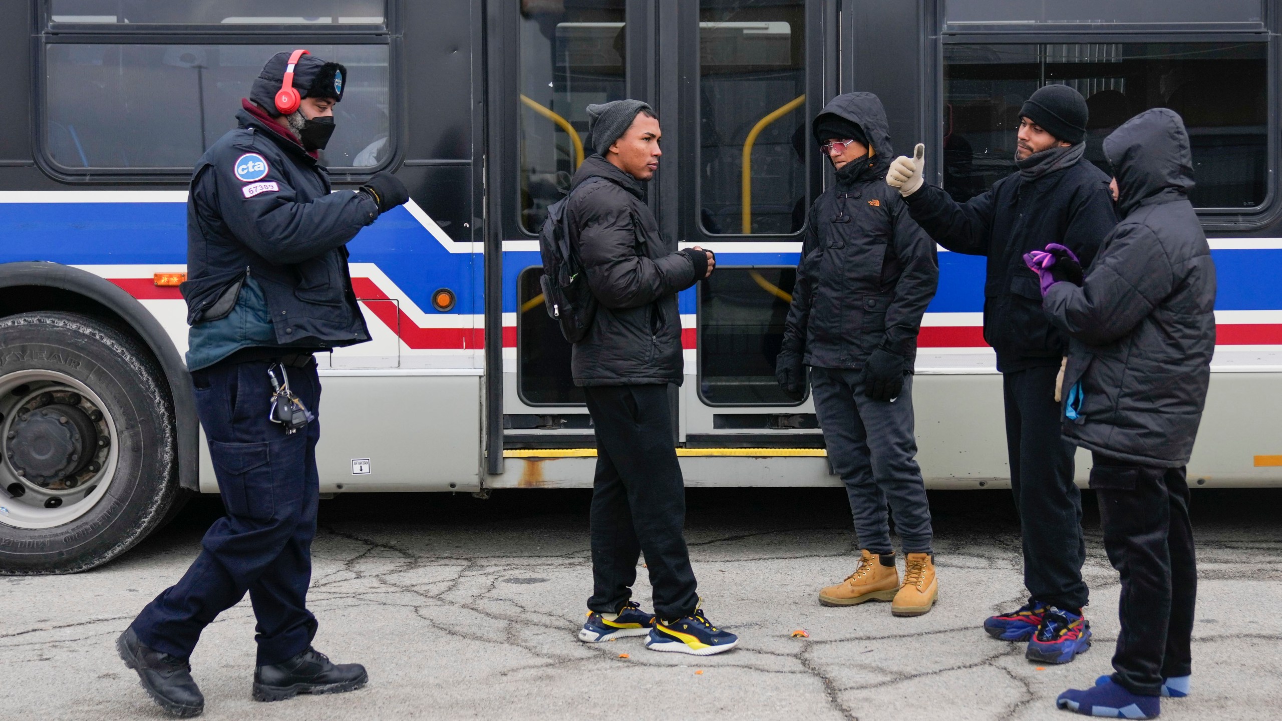 A Chicago Transit Authority worker, left, greets migrants where "warming" buses are parked in the 800 block of South Desplaines Street Thursday, Jan. 11, 2024, in Chicago. In the city of Chicago's latest attempt to provide shelter to incoming migrants, several buses were parked in the area to house people in cold winter weather. (AP Photo/Erin Hooley)