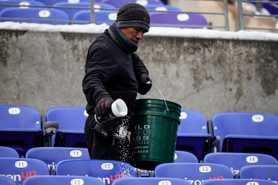 A stadium employee spreads salt in the stands before an NFL football AFC divisional playoff game between the Baltimore Ravens and the Houston Texans, Saturday, Jan. 20, 2024, in Baltimore. (AP Photo/Matt Slocum)