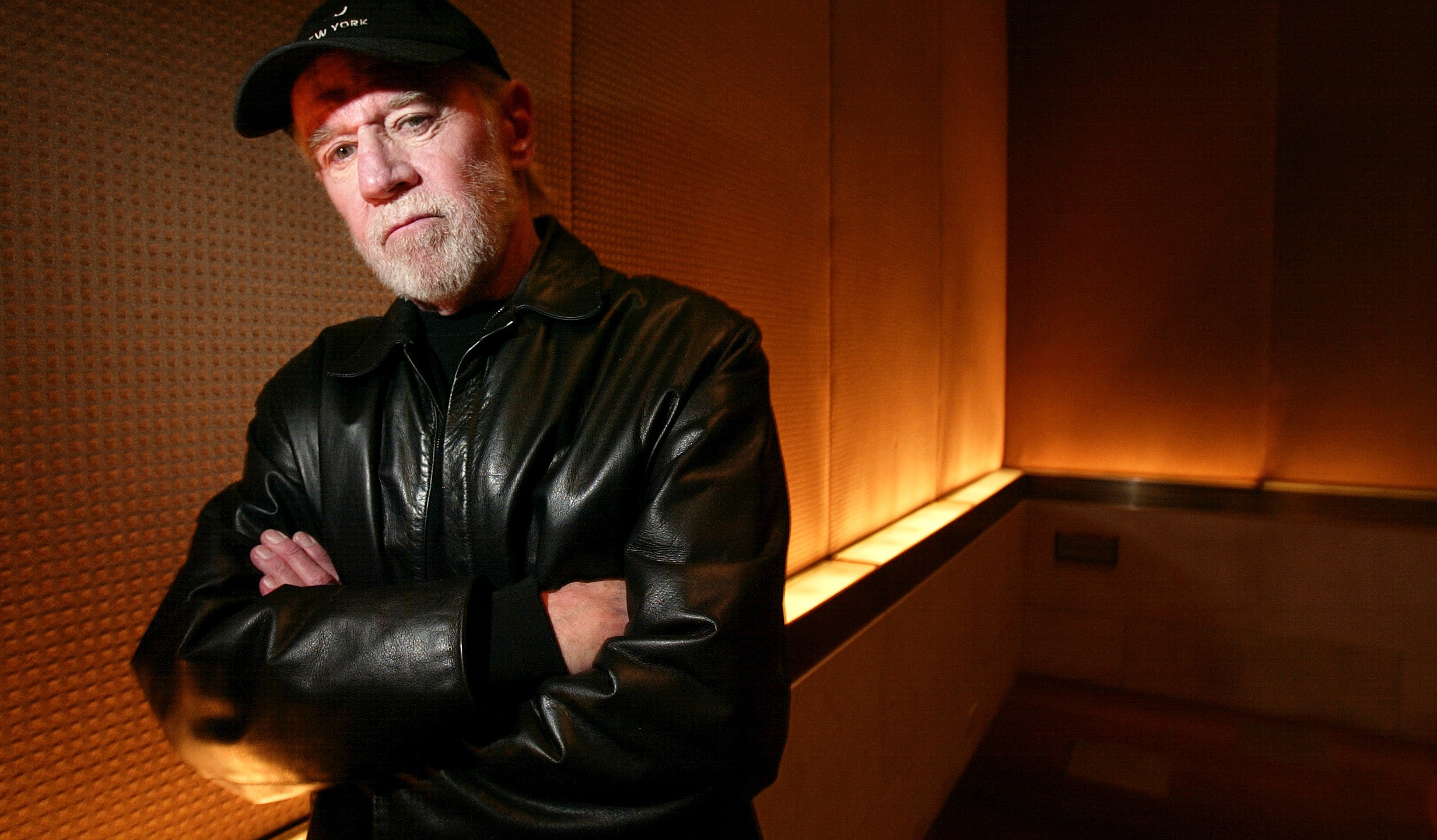 FILE - Actor and comedian George Carlin poses in a New York hotel March 19, 2004. Carlin's estate has filed a lawsuit against the media company behind a fake hourlong comedy special that purportedly uses artificial intelligence to recreate the late standup comic’s style and material. The lawsuit filed in federal court in Los Angeles on Thursday, Jan. 25, 2024, asks that a judge order the podcast outlet, Dudesy, to immediately take down the audio special, “George Carlin: I'm Glad I'm Dead," in which a synthesis of Carlin, who died in 2008, delivers commentary on current events. (AP Photo/Gregory Bull, File)