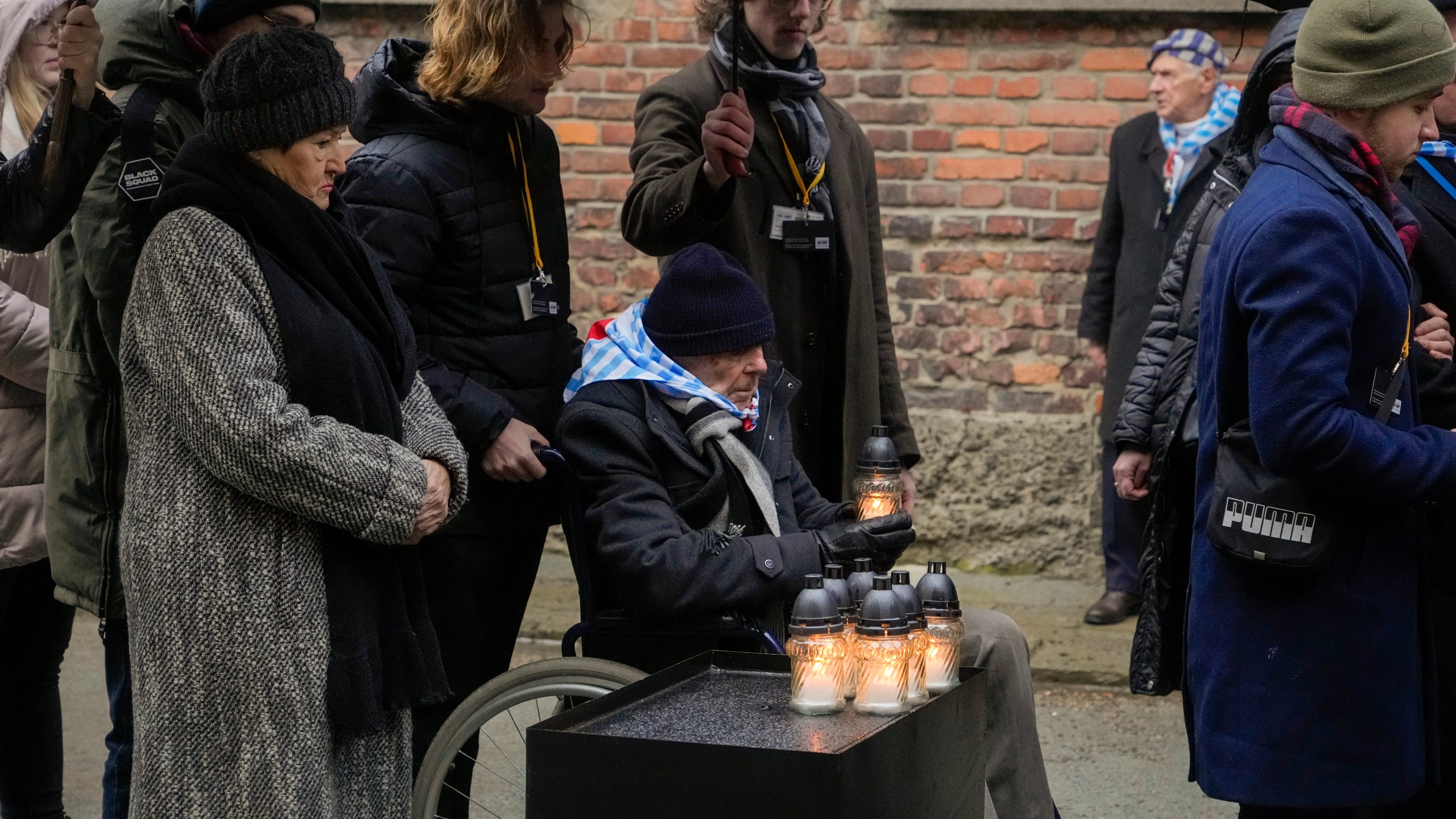 A Holocaust survivor holds a candle while waiting in line to place it next to the Death Wall at the Auschwitz Nazi death camp in Oswiecim, Poland, Saturday, Jan. 27, 2024. Survivors of Nazi death camps marked the 79th anniversary of the liberation of the Auschwitz-Birkenau camp during World War II in a modest ceremony in southern Poland.(AP Photo/Czarek Sokolowski)