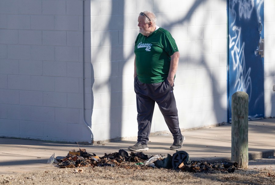 Bob Lutz, the executive director of League 42, a youth baseball league in Wichita, Kan., walks past the charred remains of a trash dumpster where pieces of a stolen Jackie Robinson statue were found by Wichita police on Tuesday, Jan. 30, 2024. The life-sized statue of baseball pioneer Jackie Robinson was cut off at the ankles from the League 42 baseball field on January 25th. Police have made no arrests in the case but said Tuesday that the statue was damaged beyond repair. (Travis Heying/The Wichita Eagle via AP)