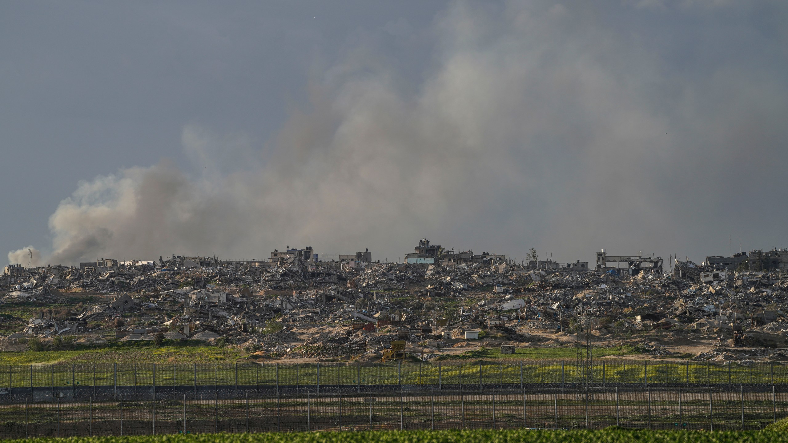 Smoke rises behind rubble from buildings destroyed in the Israeli Army's ground operation in the Gaza Strip as seen from southern Israel, adjacent to the Gaza border fence, Thursday, Feb. 1, 2024. (AP Photo/Tsafrir Abayov)