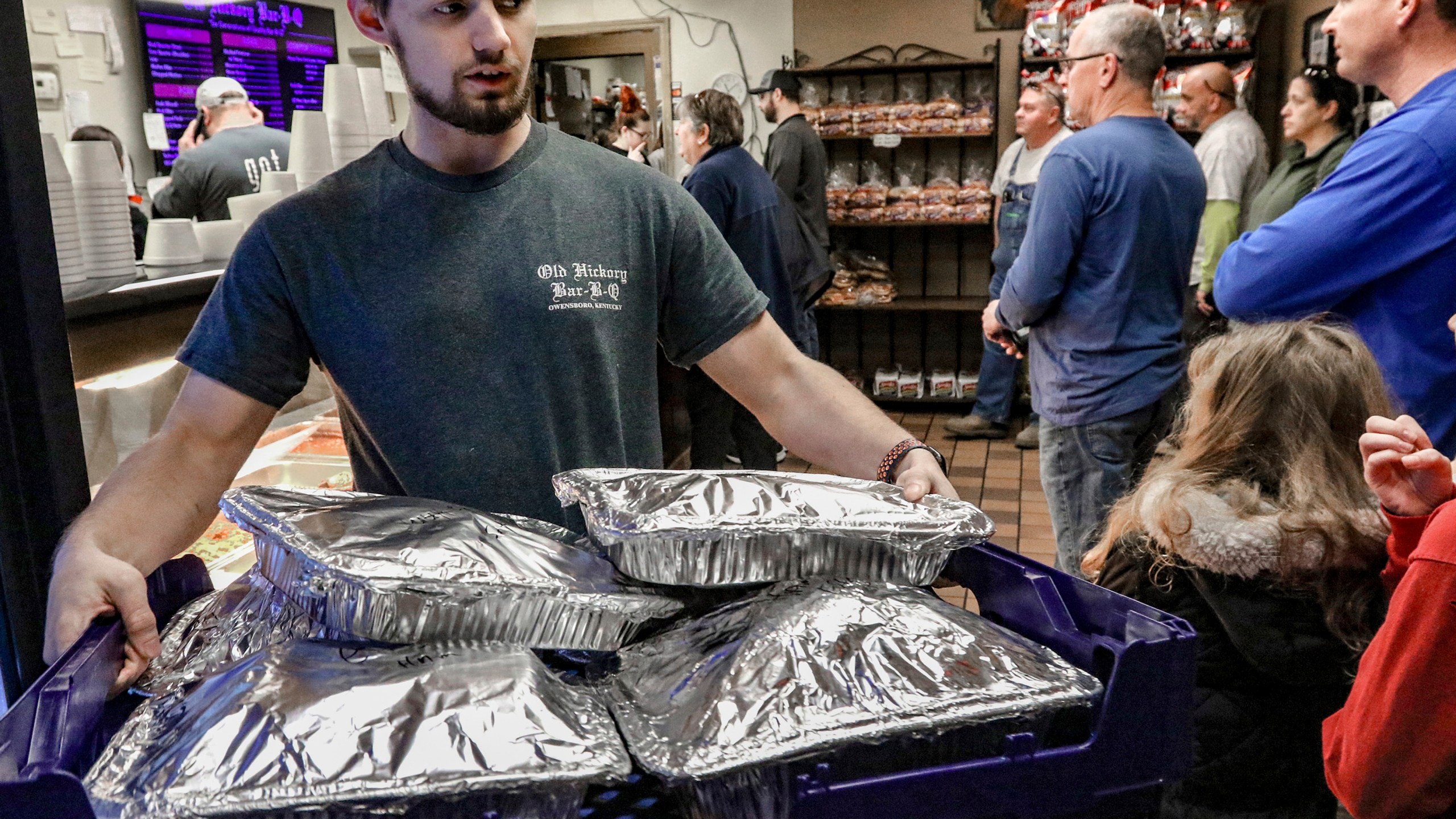 File - Old Hickory Bar-B-Que employee Tyler Reynolds carries a tray of sliced hams of the the restaurant on Dec. 22, 2023, in Owensboro, Ky. On Friday, Feb. 2, 2024, the U.S. government issues its January jobs report. (Greg Eans/The Messenger-Inquirer via AP, File)