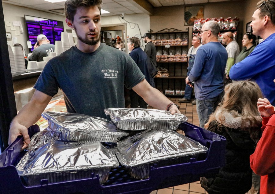 File - Old Hickory Bar-B-Que employee Tyler Reynolds carries a tray of sliced hams of the the restaurant on Dec. 22, 2023, in Owensboro, Ky. On Friday, Feb. 2, 2024, the U.S. government issues its January jobs report. (Greg Eans/The Messenger-Inquirer via AP, File)