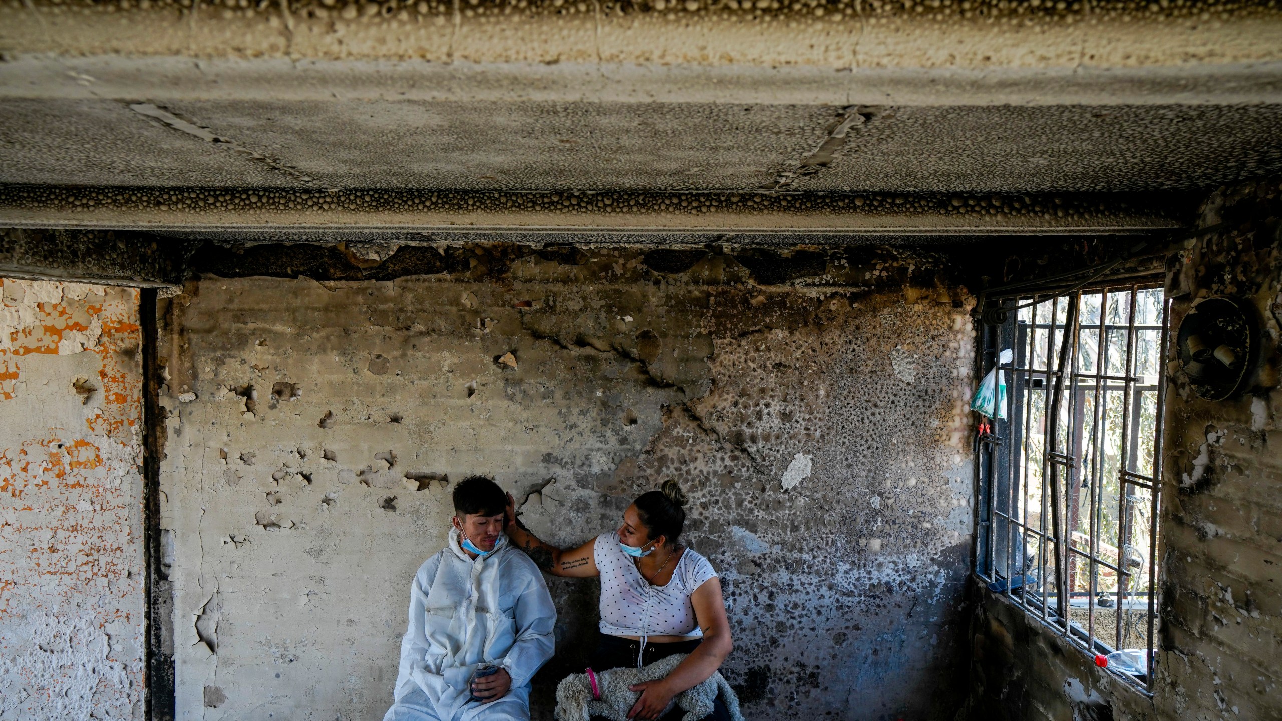 Camila Lange, who is 7-months-pregnant, and her husband Felipe Corvalan sit with their dog Florencia inside their home that was burned by a deadly wildfire in Vina del Mar, Chile, Monday, Feb. 5, 2024. (AP Photo/Esteban Felix)