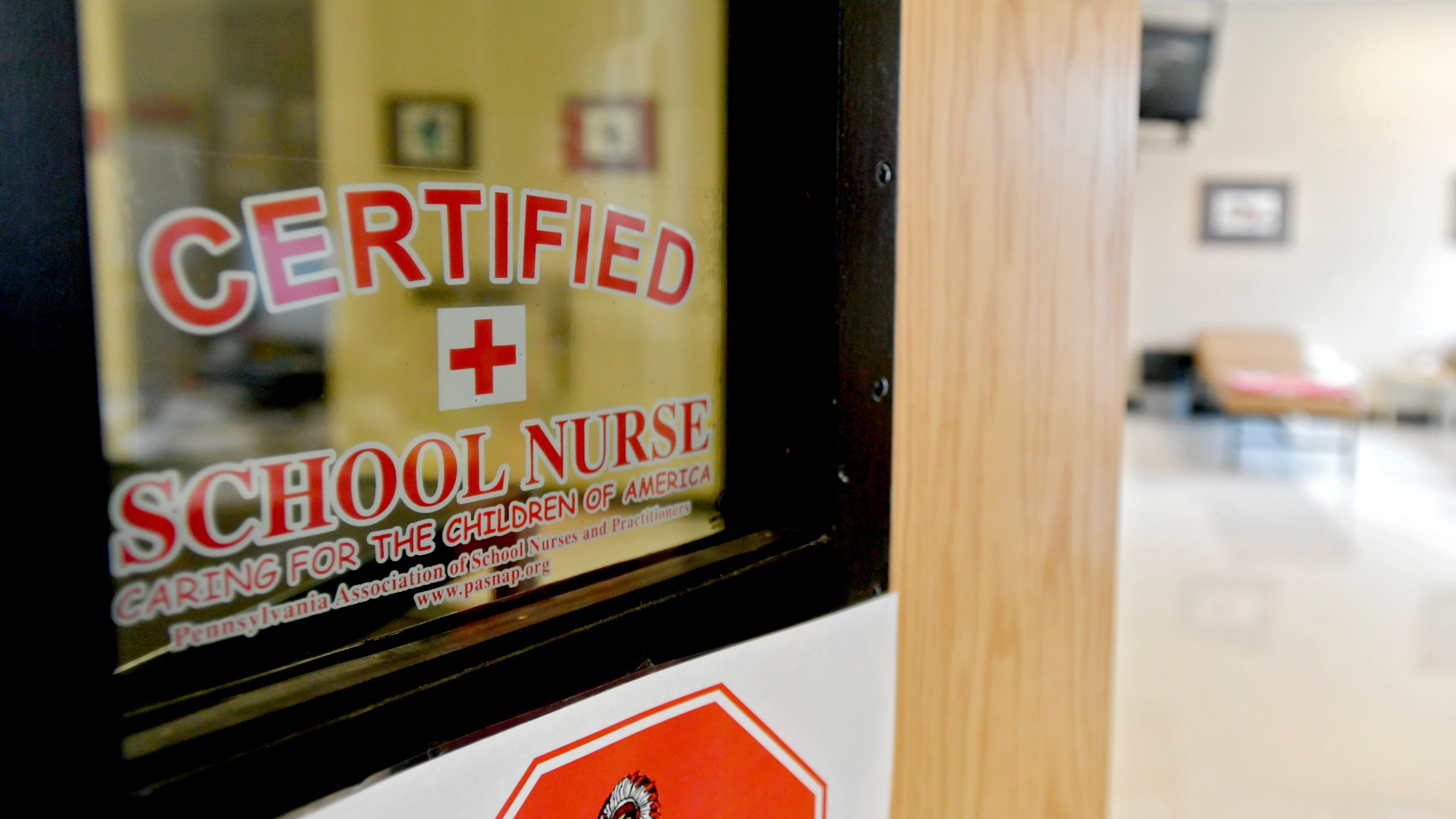 This photo taken Aug. 15, 2016, shows the front of the Bellefonte Area School District certified school nurses office. Schools are confronting soaring absence rates. Some are calling for parents to send their children to class even if they are not feeling 100% well. During the pandemic, schools urged parents and children to stay home at any sign of illness. Now that the COVID-19 emergency has ended, guidance on when to keep children home varies widely. The American Academy of Pediatrics recommends staying home with fever, vomiting or diarrhea, or when students “are not well enough to participate in class.” But many districts go far beyond that, delineating a dizzying array of symptoms they say should rule out attendance. (Abby Drey/Centre Daily Times via AP, file)