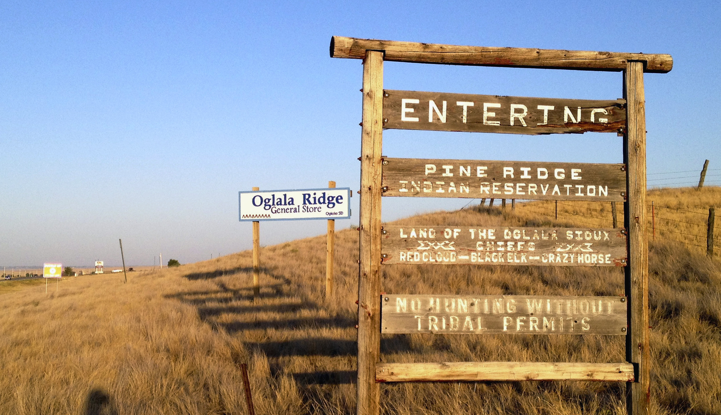 FILE - A sign hands outside the entrance to the Pine Ridge Indian Reservation in South Dakota, home to the Oglala Sioux tribe, Sept. 9, 2012. A tribe has banned Republican Gov. Kristi Noem from the Pine Ridge Reservation after she spoke this week about wanting to send razor wire and security personnel to Texas to help deter immigration at the U.S.-Mexico border and also said cartels are infiltrating the state's reservations. (AP Photo/Kristi Eaton, File)