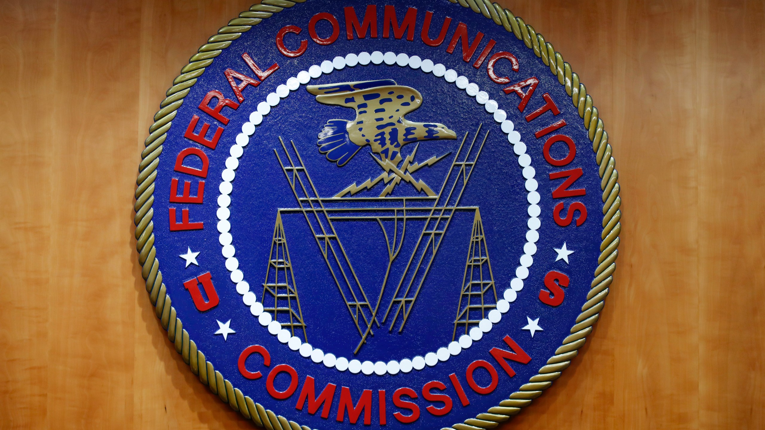 FILE - The seal of the Federal Communications Commission (FCC) is seen before an FCC meeting to vote on net neutrality, Dec. 14, 2017, in Washington. The FCC is announcing that it will outlaw all robocalls featuring AI-generated voices under the existing Telephone Consumer Protection Act. The news comes after celebrities and politicians, including President Joe Biden, have been impersonated using the technology. (AP Photo/Jacquelyn Martin, File)