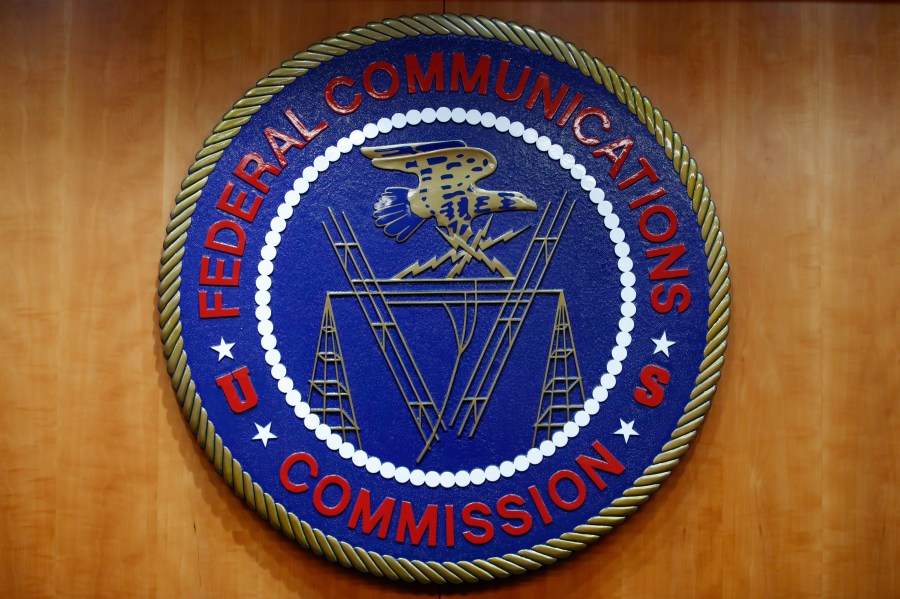 FILE - The seal of the Federal Communications Commission (FCC) is seen before an FCC meeting to vote on net neutrality, Dec. 14, 2017, in Washington. The FCC is announcing that it will outlaw all robocalls featuring AI-generated voices under the existing Telephone Consumer Protection Act. The news comes after celebrities and politicians, including President Joe Biden, have been impersonated using the technology. (AP Photo/Jacquelyn Martin, File)