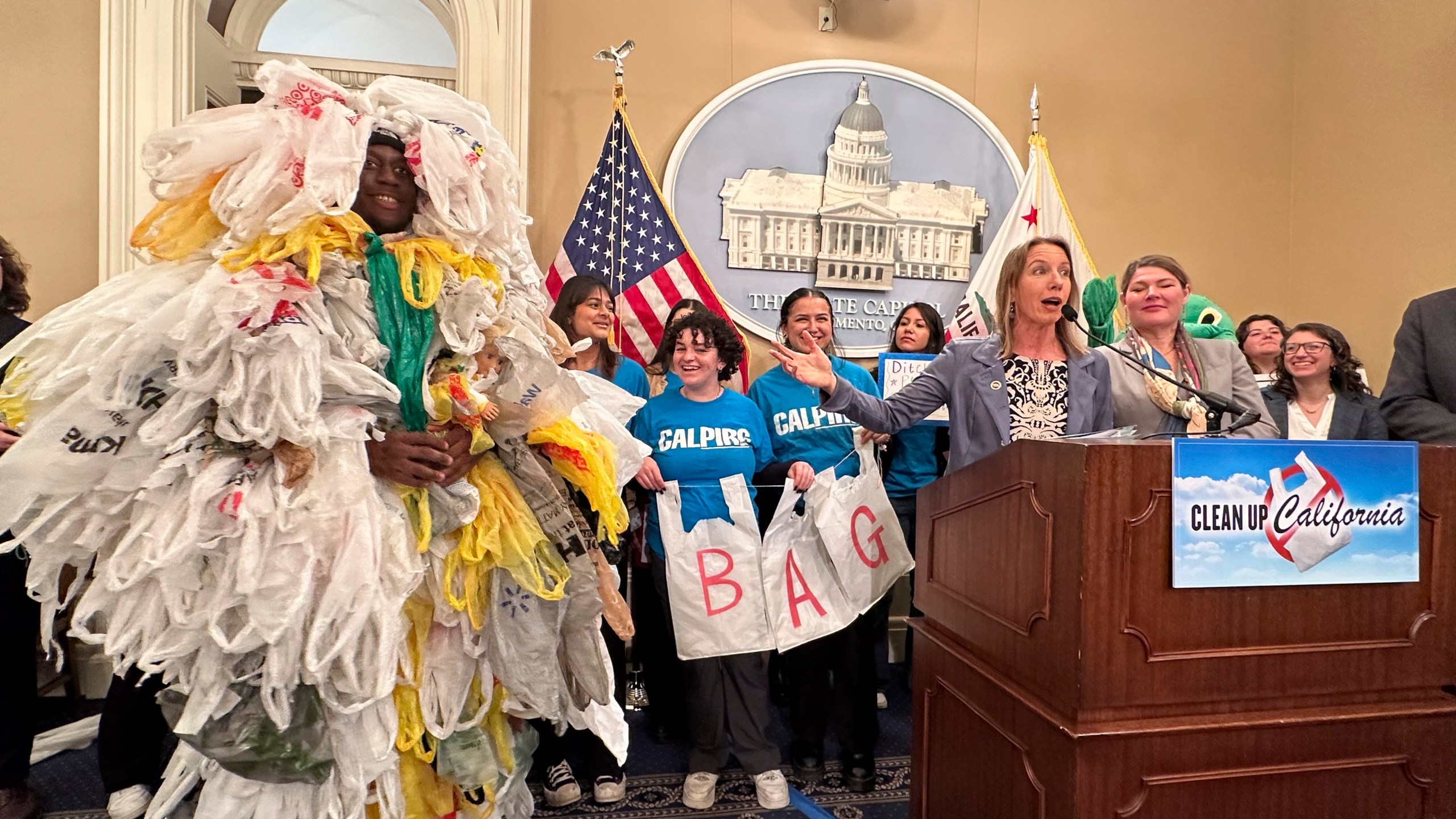 California Democratic state Sen. Catherine Blakespear gestures toward a person covered in plastic bags during a news conference at the Capitol in Sacramento, Calif., on Thursday, Feb. 8, 2024. Blakespear has authored a bill that would ban all plastic shopping bags in California. (AP/Adam Beam)