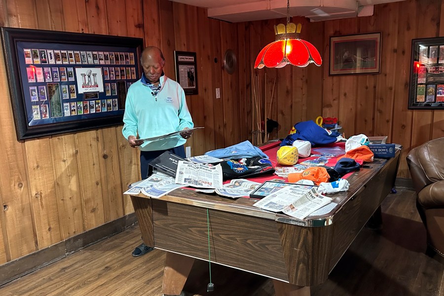 Gregory Eaton looks at some Super Bowl memorabilia at his home, Tuesday, Jan. 30, 2024 in Lansing, Mich. Eaton is a member of the exclusive "never missed a Super Bowl" club. He and two friends, all in their 80s, plan to be in Las Vegas on Sunday for Super Bowl 58. (AP Photo/Mike Householder)