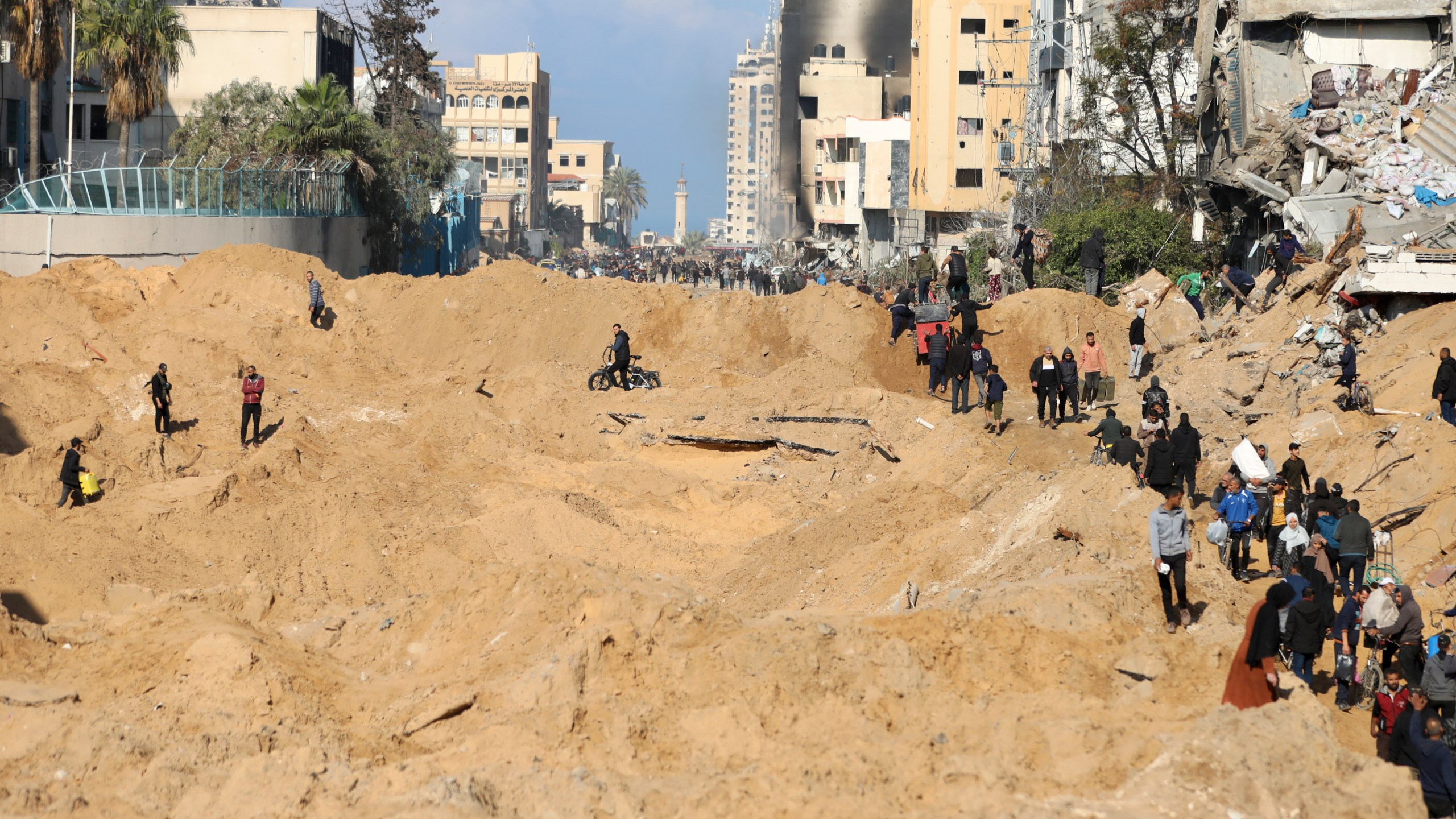 Palestinians walk through the destruction left by the Israeli air and ground offensive on the Gaza Strip in Gaza City, Saturday, Feb. 10, 2024. (AP Photo/Mohammed Hajjar)