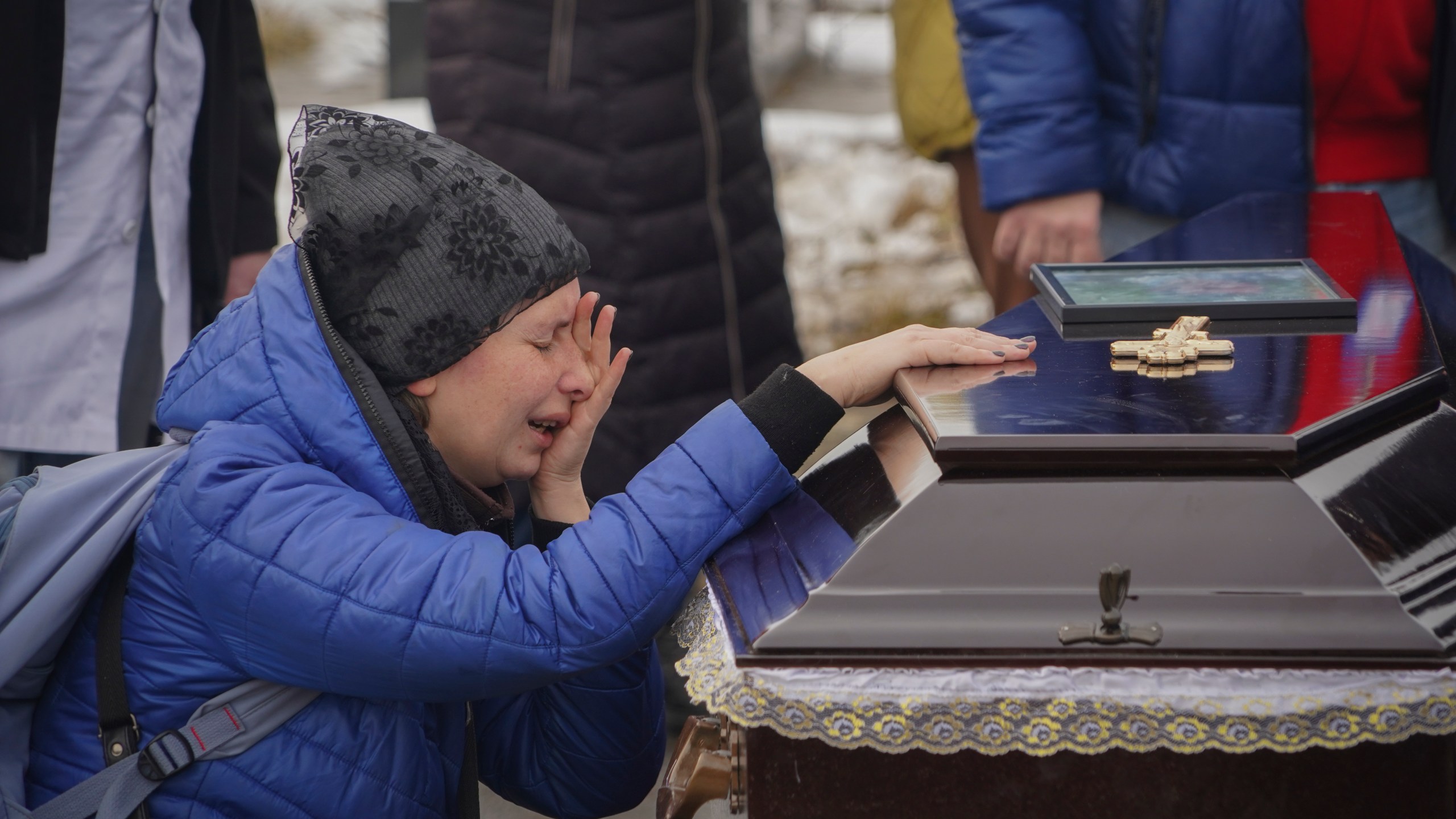 People mourn over the coffins of a family killed in a fire when Russian drone hit their home in residential neighbourhood in Kharkiv, Ukraine, Monday, Feb. 12, 2024. Seven people including three children were killed on Saturday in the Russian drone attack. (AP Photo/Andrii Marienko)