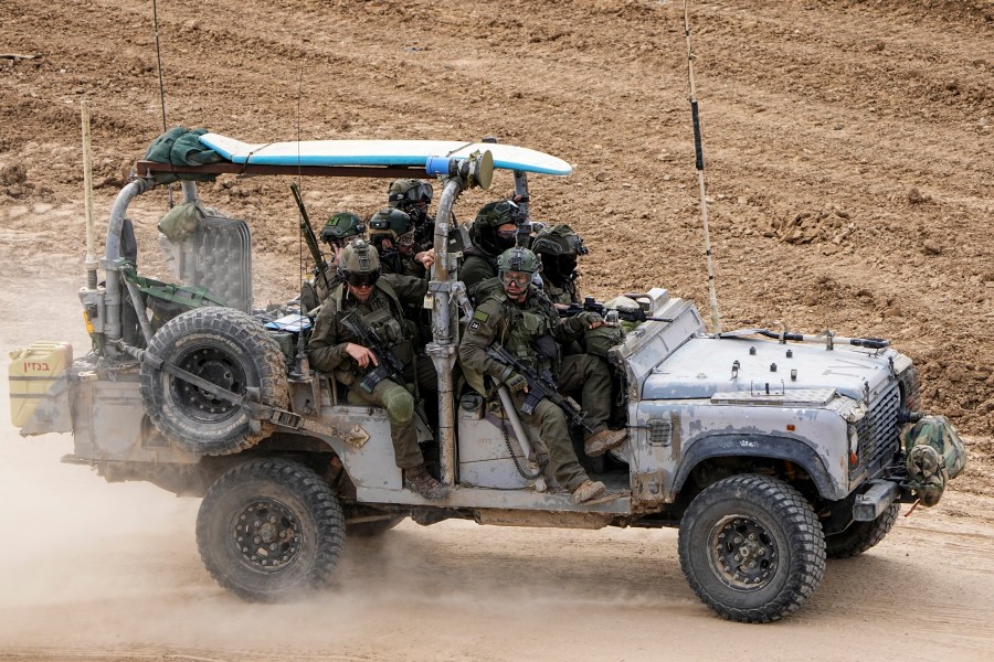 Israeli soldiers with a surfboard on the roof of their vehicle drive towards the Gaza Strip, in southern Israel, Tuesday, Feb. 13, 2024. The army is battling Palestinian militants across Gaza in the war ignited by Hamas' Oct. 7 attack into Israel. (AP Photo/Ariel Schalit)