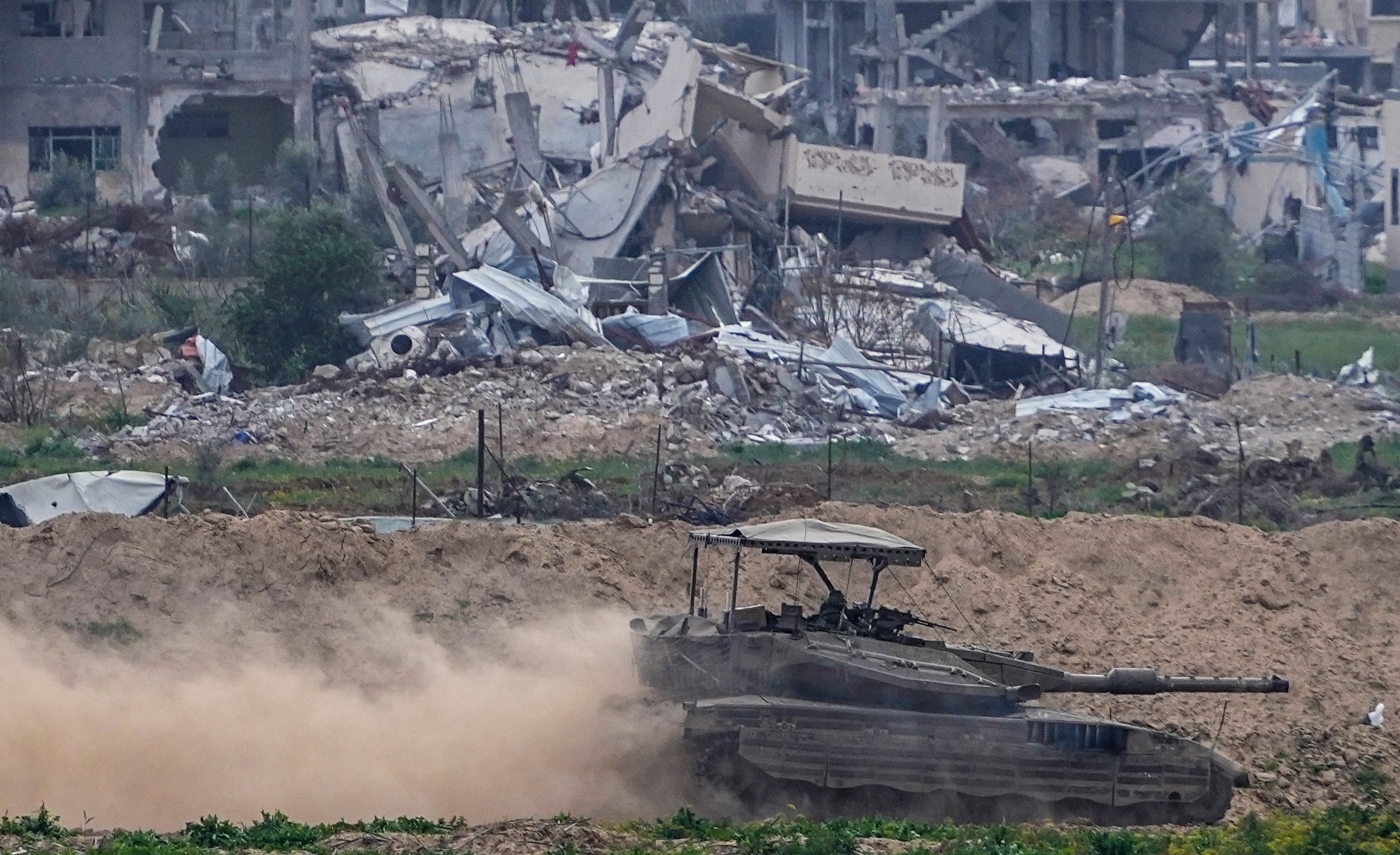 Israeli soldiers drive a tank inside the Gaza Strip, as seen from southern Israel, Tuesday, Feb. 13, 2024. The army is battling Palestinian militants across Gaza in the war ignited by Hamas' Oct. 7 attack into Israel. (AP Photo/Ariel Schalit)