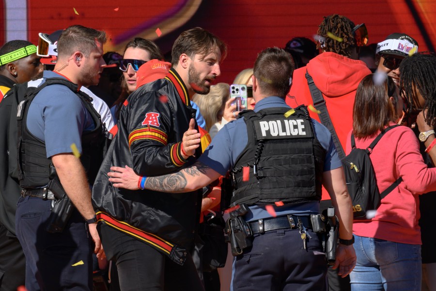 Police escort Kansas City Chiefs tight end Noah Gray and his teammates off the stage after a shooting following their victory parade and rally in Kansas City, Mo., Wednesday, Feb. 14, 2024. Authorities in Kansas City are trying to decipher who was behind the mass shooting that unfolded Wednesday. (AP Photo/Reed Hoffmann)