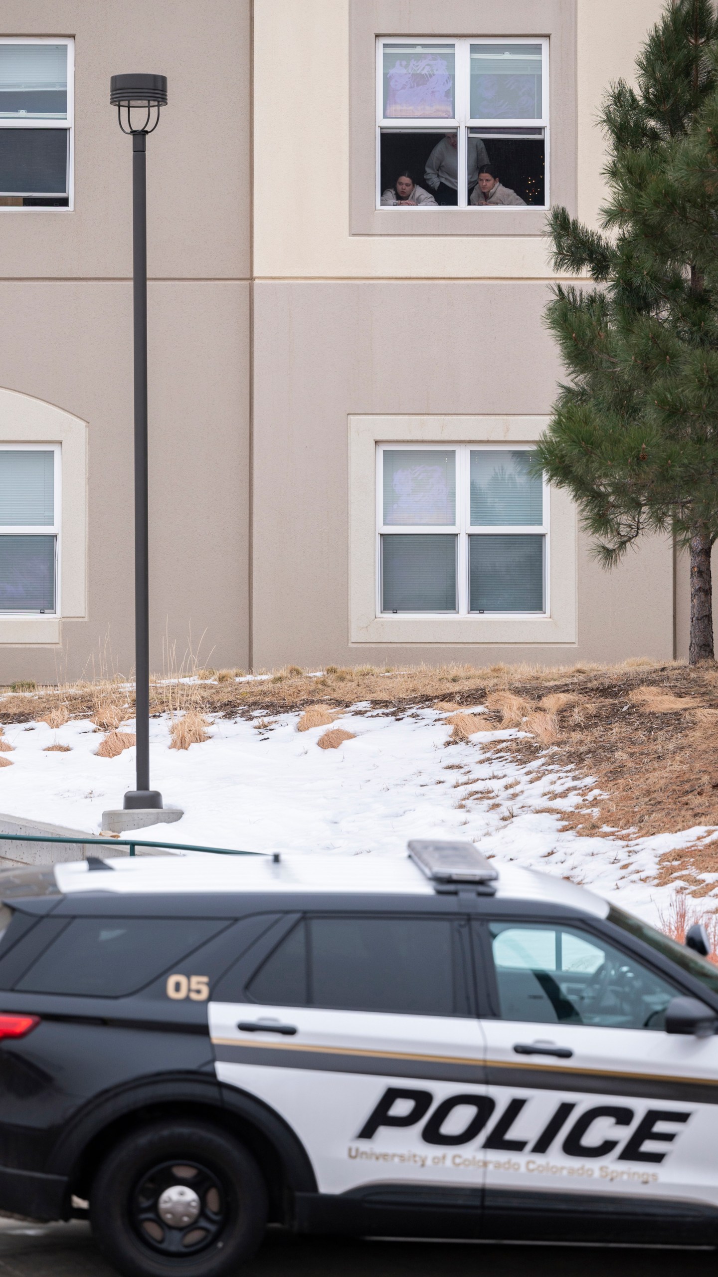 Students look outside their dorm window in the Village at Alpine Valley housing, Friday, Feb. 16, 2024, as police investigate a shooting on the University of Colorado Colorado Springs campus in Colorado Springs, Colo. (Christian Murdock/The Gazette via AP)