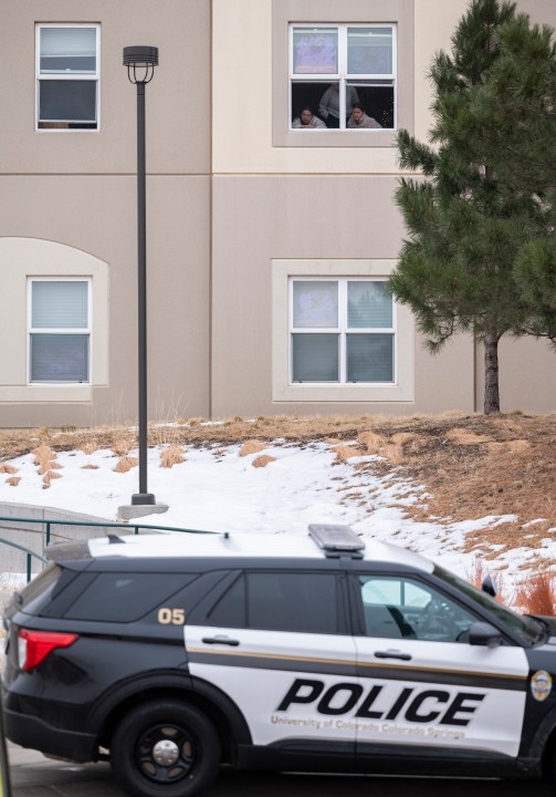 Students look outside their dorm window in the Village at Alpine Valley housing, Friday, Feb. 16, 2024, as police investigate a shooting on the University of Colorado Colorado Springs campus in Colorado Springs, Colo. (Christian Murdock/The Gazette via AP)