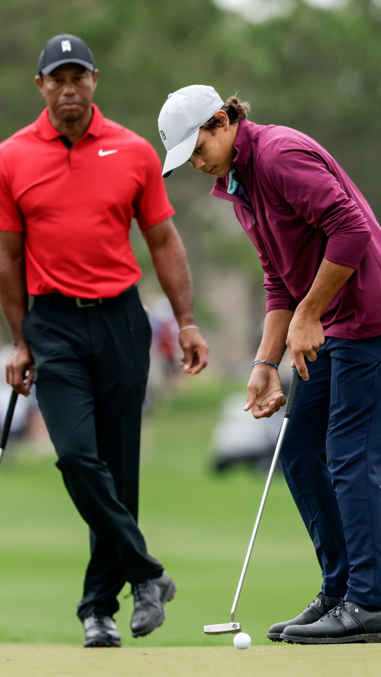 FILE -Tiger Woods, left, watches his son Charlie, right, putt ball during the final round of the PNC Championship golf tournament Sunday, Dec. 17, 2023, in Orlando, Fla. Charlie Woods, 15, will be playing a pre-qualifier on Thursday in Hobe Sound, Fla., the first step before a full qualifier for the Cognizant Classic on the PGA Tour. (AP Photo/Kevin Kolczynski, File)