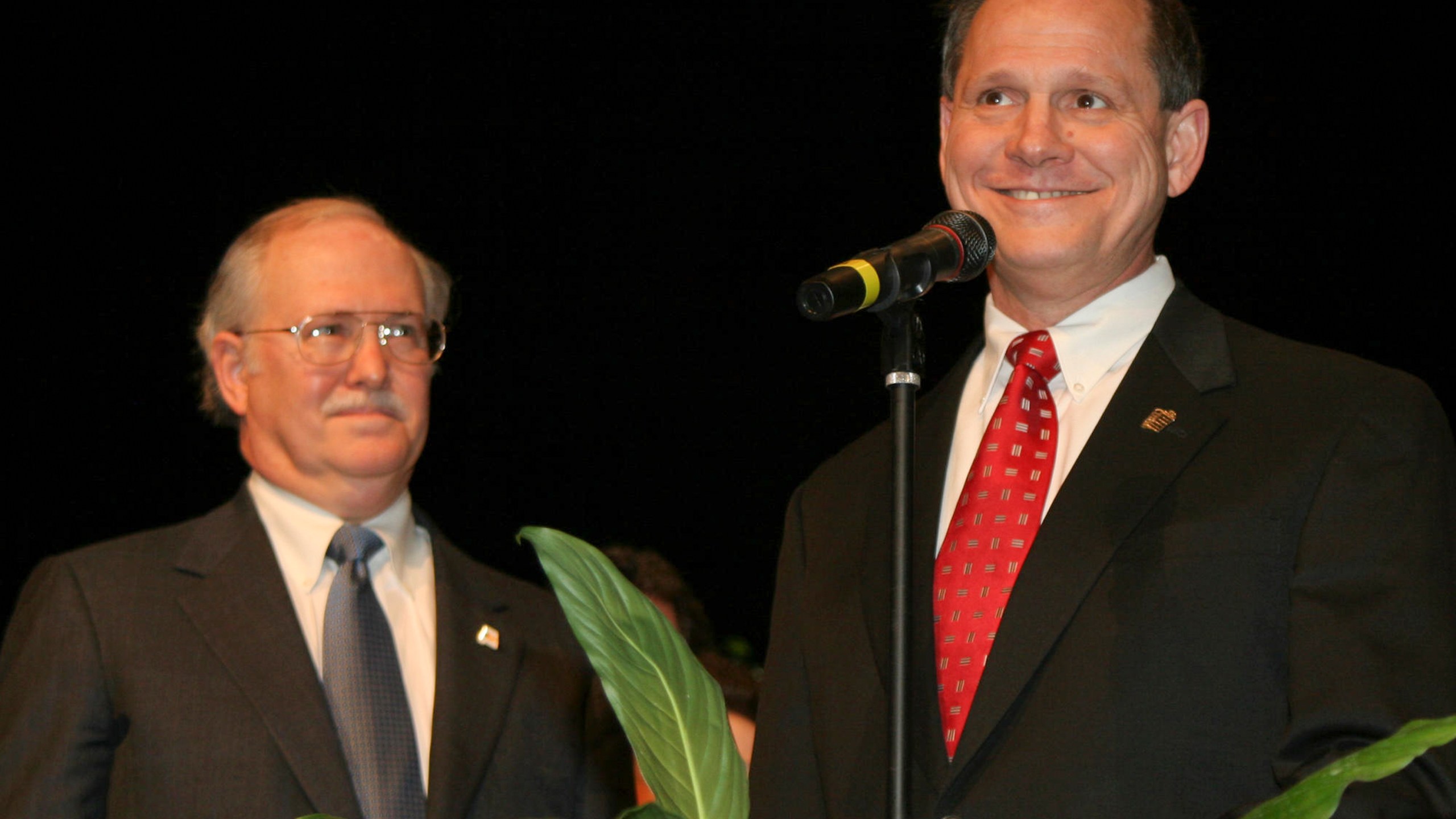 FILE - Tom Parker, left, listens as former Alabama Supreme Court Chief Justice Roy Moore, right, addresses the crowd at the Davis Theater in Montgomery, Ala. on Jan. 14, 2005, before swearing in Parker as an associate justice of the court. When the Alabama Supreme Court ruled that frozen embryos are children, its Chief Justice Tom Parker made explicit use of Christian theology to justify the court's decision in his concurrence, where his language echoed the broader anti-abortion movement. Parker is no stranger to church-state debates. He served as former Chief Justice Moore's spokesperson during fights over a Ten Commandments monument that Moore erected in the Alabama Supreme Court building. (AP Photo/Jay Sailors, File)