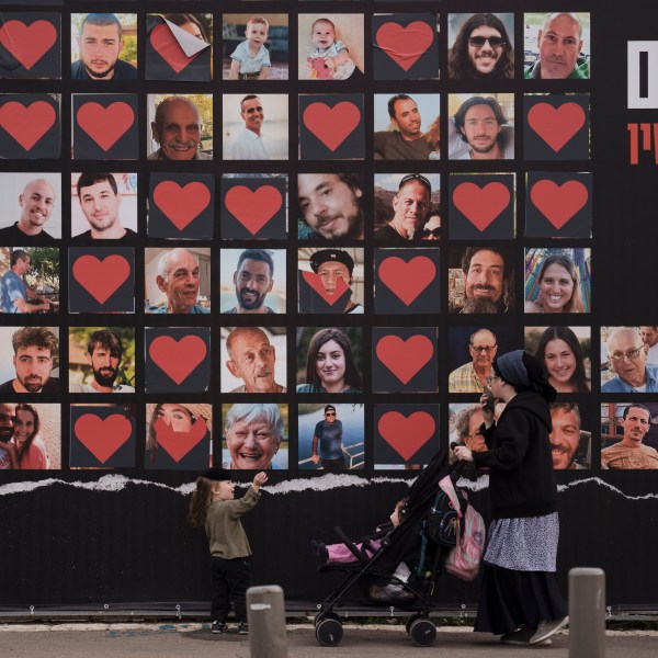 FILE - A woman and her children walk past a wall with photographs of hostages who were kidnapped during the Oct. 7 Hamas cross-border attack in Israel in Jerusalem, Israel, Monday, Feb. 26, 2024. Israel and Hamas are inching toward a new deal that would free some of the roughly 130 hostages held in the Gaza Strip in exchange for a weeks-long pause in the war, now in its fifth month. A deal would bring some respite to desperate people in Gaza, who have borne a staggering toll in the war, as well as to the anguished families of hostages taken during Hamas' Oct. 7 attack that sparked the war. (AP Photo/Leo Correa, File)