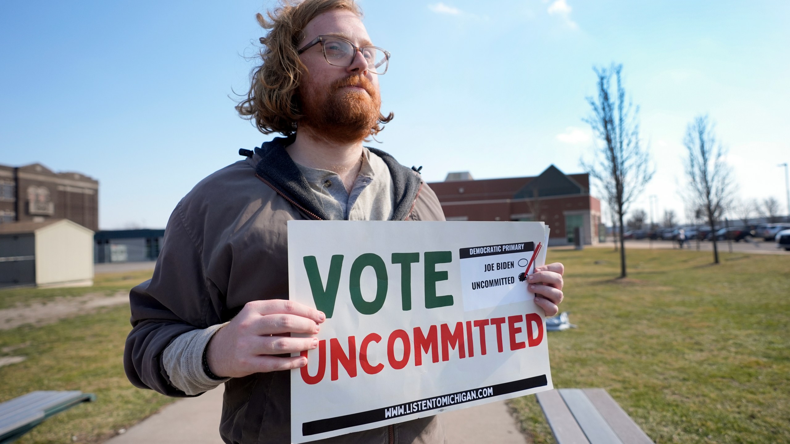 Eric Suter-Bull holds a Vote Uncommitted sign outside a voting location at Saline Intermediate School for the Michigan primary election in Dearborn, Mich., Tuesday, Feb. 27, 2024. Michigan is the last major primary state before Super Tuesday and a critical swing state in November's general election. (AP Photo/Paul Sancya)