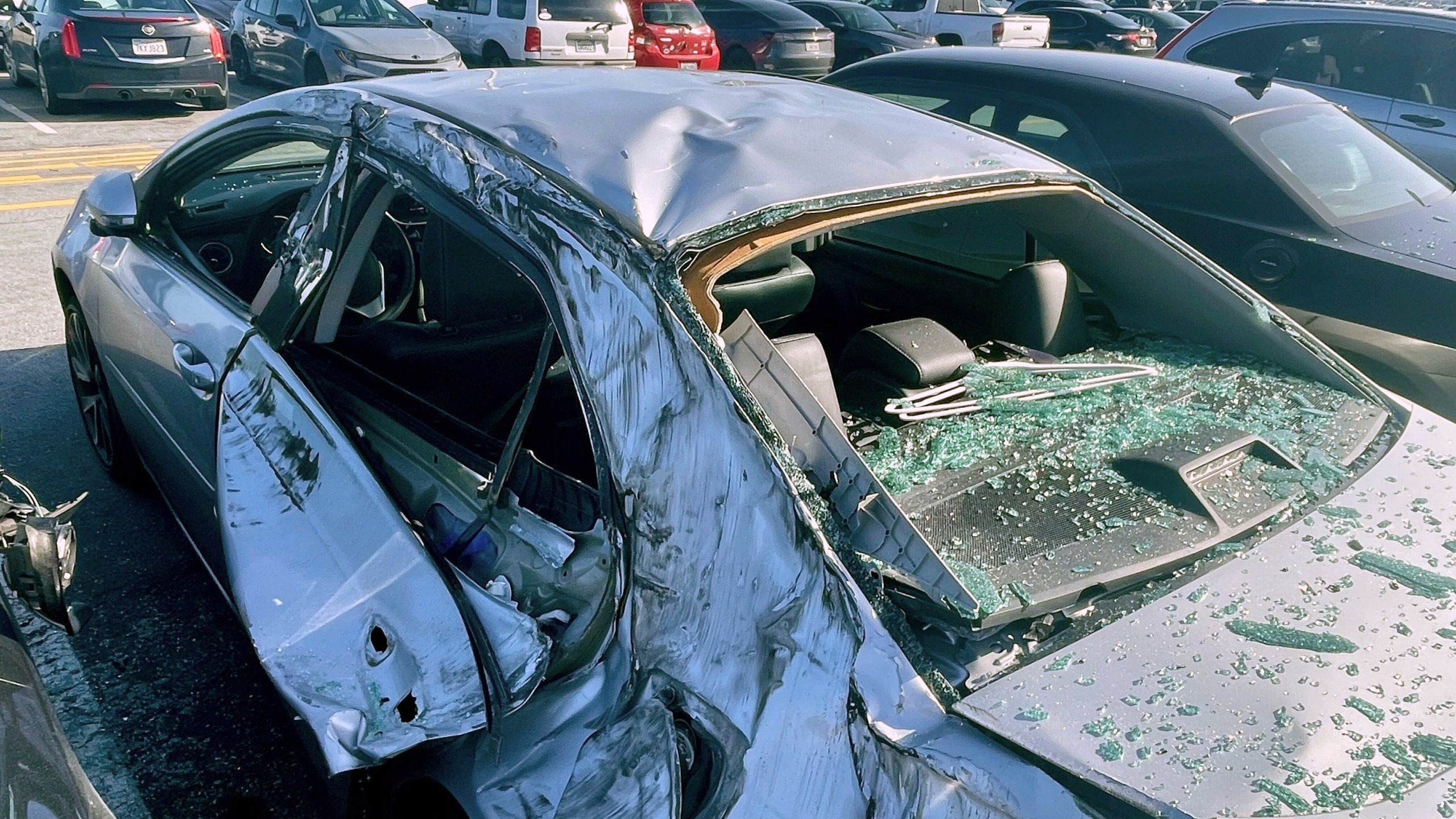 A damaged car is seen in an on-airport employee parking lot after tire debris from a Boeing 777 landed on it at San Francisco International Airport, Thursday, March 7, 2024. A United Airlines jetliner bound for Japan made a safe landing in Los Angeles on Thursday after losing a tire while taking off from San Francisco. (AP Photo/Haven Daley)