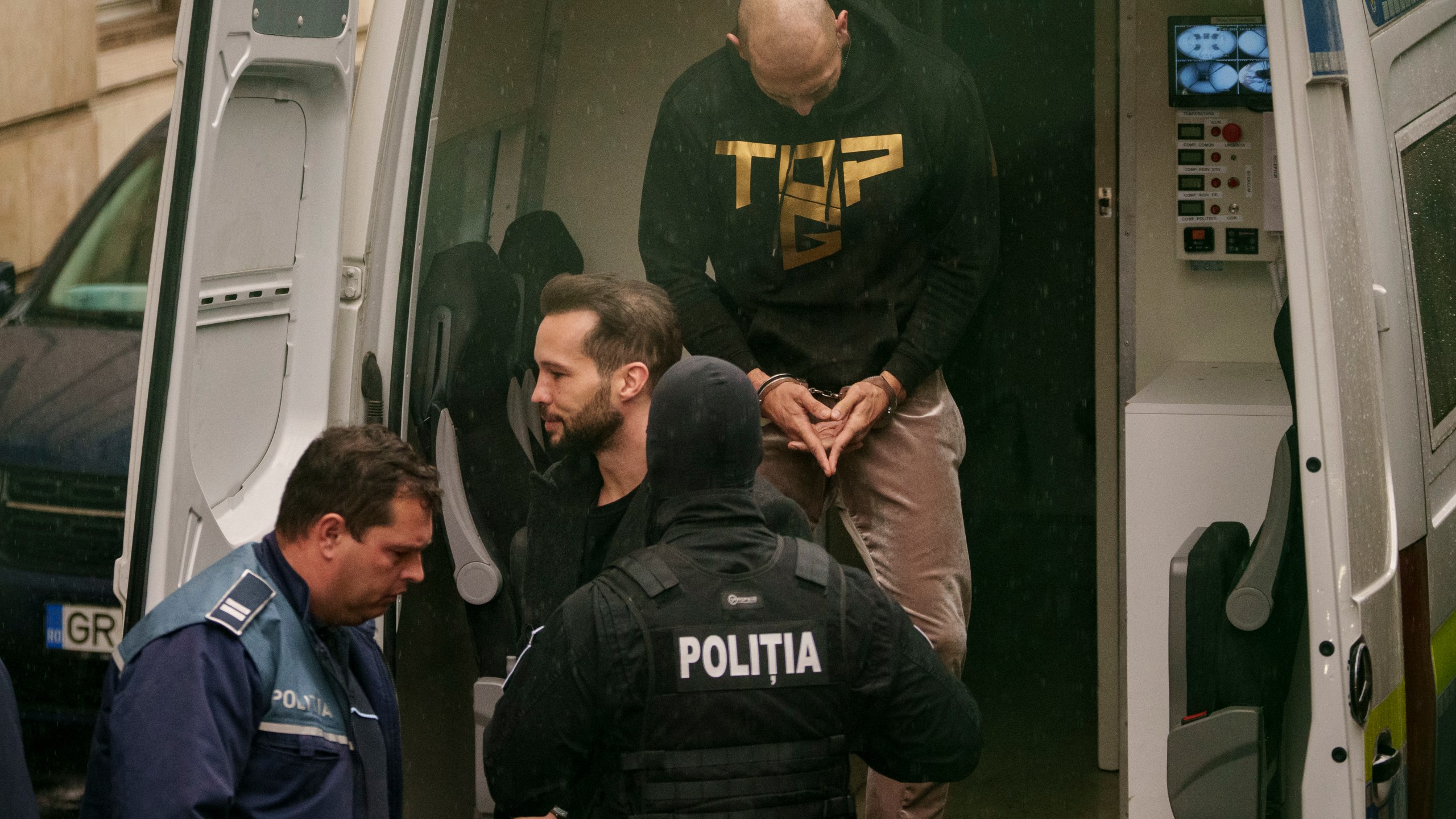 Police officers escort Andrew Tate, center, handcuffed, next to his brother Tristan to the Court of Appeal in Bucharest, Romania, Tuesday, March 12, 2024. Online influencer Andrew Tate was detained in Romania and handed an arrest warrant issued by British authorities, his spokesperson said Tuesday. (AP Photo/Andreea Alexandru)