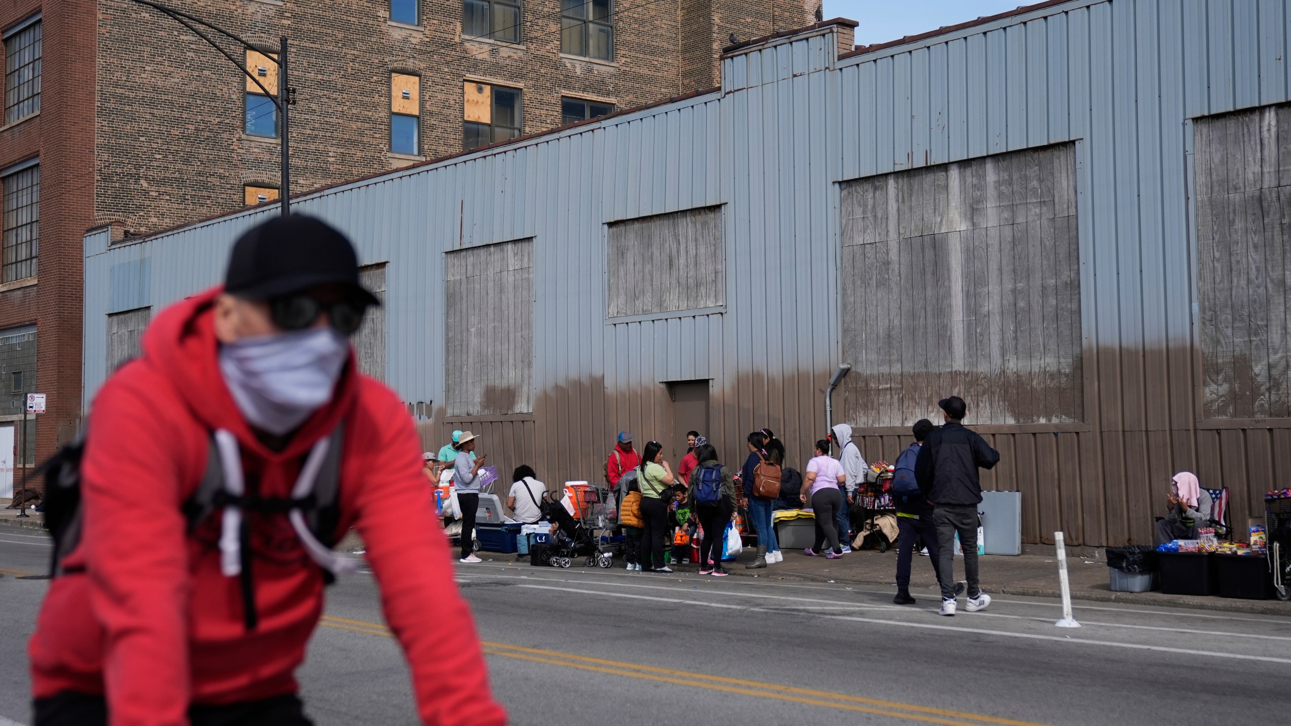 People hang around outside of a migrant shelter Wednesday, March 13, 2024, in the Pilsen neighborhood of Chicago. Multiple people living at the shelter for migrants have tested positive for measles since last week. A team from the Centers for Disease Control and Prevention is supporting local officials' response. (AP Photo/Erin Hooley)