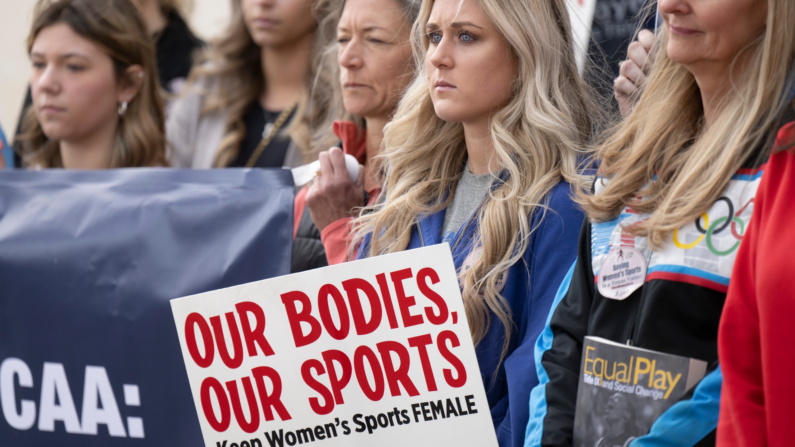 FILE - Former University of Kentucky swimmer Riley Gaines, second from right, stands during a rally on Thursday, Jan. 12, 2023, outside of the NCAA Convention in San Antonio. Gaines was among more than a dozen college athletes who filed a lawsuit against the NCAA on Thursday, March 14, 2023, accusing it of violating their Title IX rights by allowing Lia Thomas to compete at national championships in 2022. (AP Photo/Darren Abate, File)