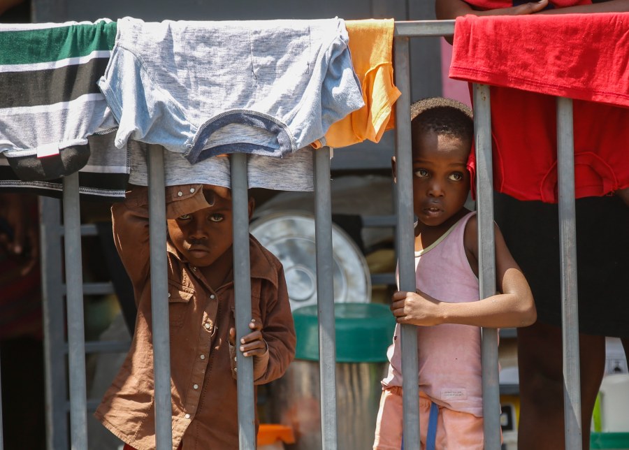 Children look through a fence at a shelter for families displaced by gang violence, in Port-au-Prince, Haiti, Wednesday, March 13, 2024. (AP Photo/Odelyn Joseph)