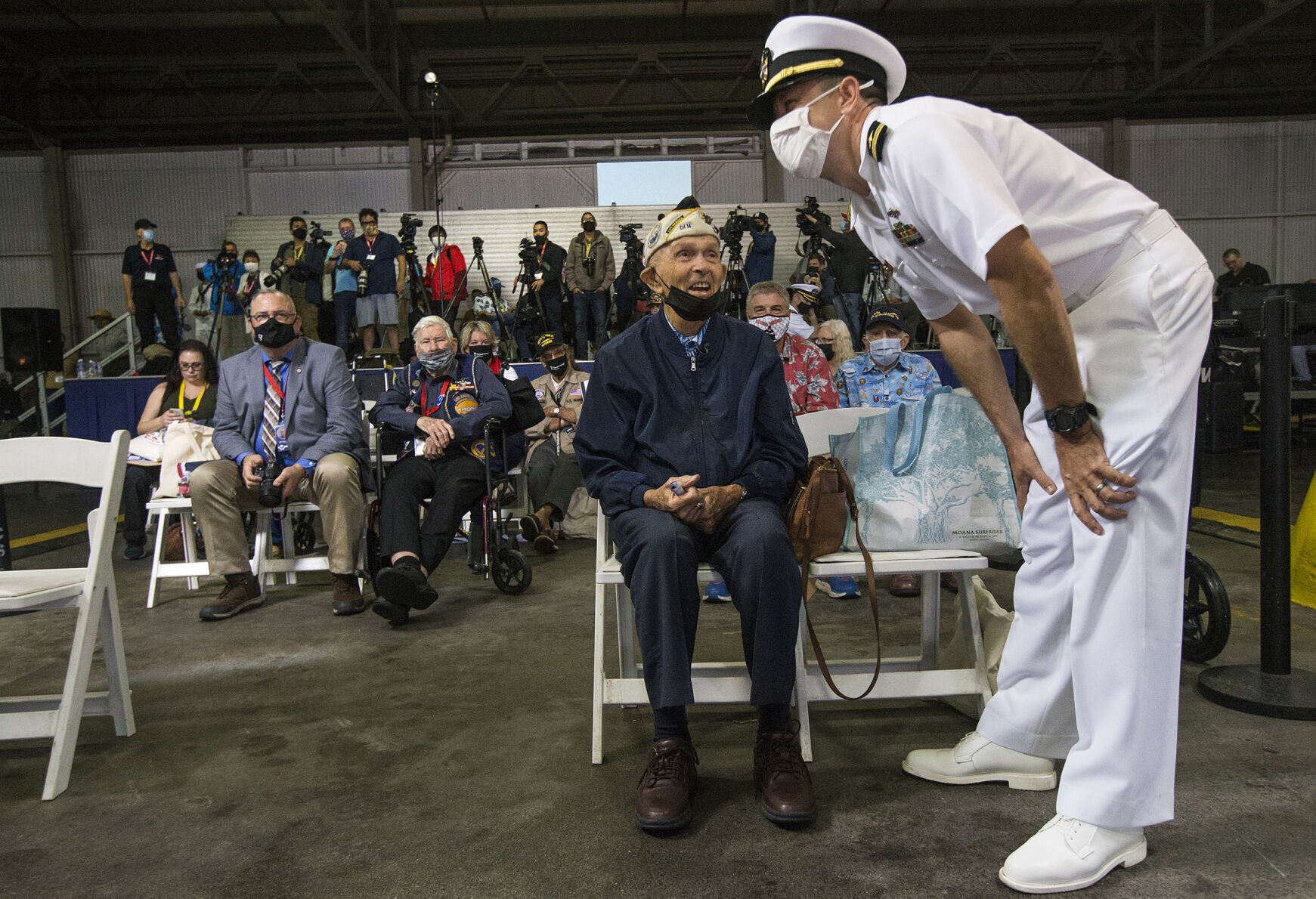 Lt. Chip Lewis speaks with Dick Higgins after helping to escort him to his seat prior to the start of the 80th commemoration of the attack on Pearl Harbor, Dec. 7, 2021, at Kilo Pier on Joint Base Pearl Harbor-Hickam in Honolulu. Higgins, one of the few remaining survivors of the Japanese attack on Pearl Harbor, died Tuesday, March 19, 2024, at his home in Bend, Ore. He was 102. (Ryan Brennecke/The Bulletin via AP)