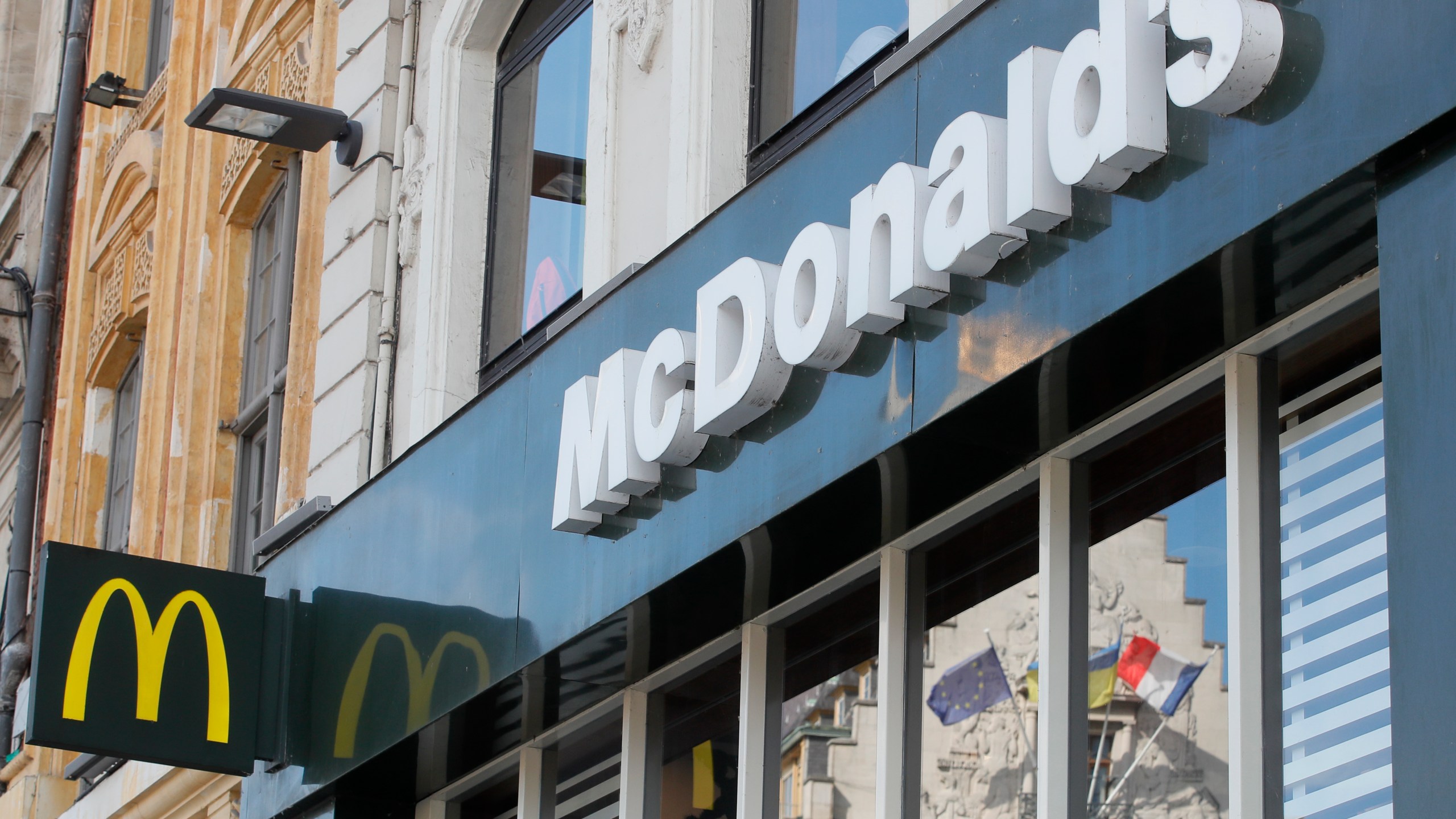 FILE - A French and a European flags are reflected in the shop window of a McDonald's restaurant in Lille, northern France, Thursday, June 16, 2022 . McDonald’s will become the title sponsor of the French soccer league from July for the next three seasons, the league said on Thursday, March 21, 2024. (AP Photo/Michel Spingler, File)